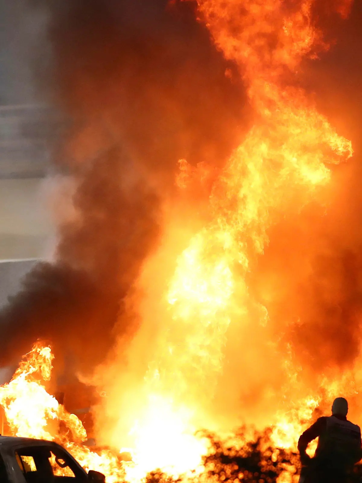 FILE - Staff extinguish flames from Haas driver Romain Grosjean's car after a crash during the Formula One race in Bahrain International Circuit in Sakhir, Bahrain, in this Sunday, Nov. 29, 2020, file photo. Mercedes announced Wednesday, May 5, 2021, that Grosjean will drive Lewis Hamilton’s 2019 championship-winning car at the French Grand Prix on June 27 before a full test day at Circuit Paul Ricard two days later. (Brynn Lennon/Pool via AP, File)