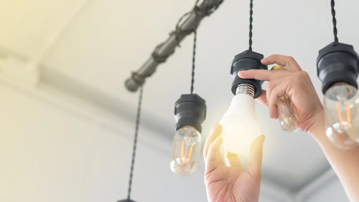 LED light Power saving concept. Asia man changing compact-fluorescent (CFL) bulbs with new bulb.