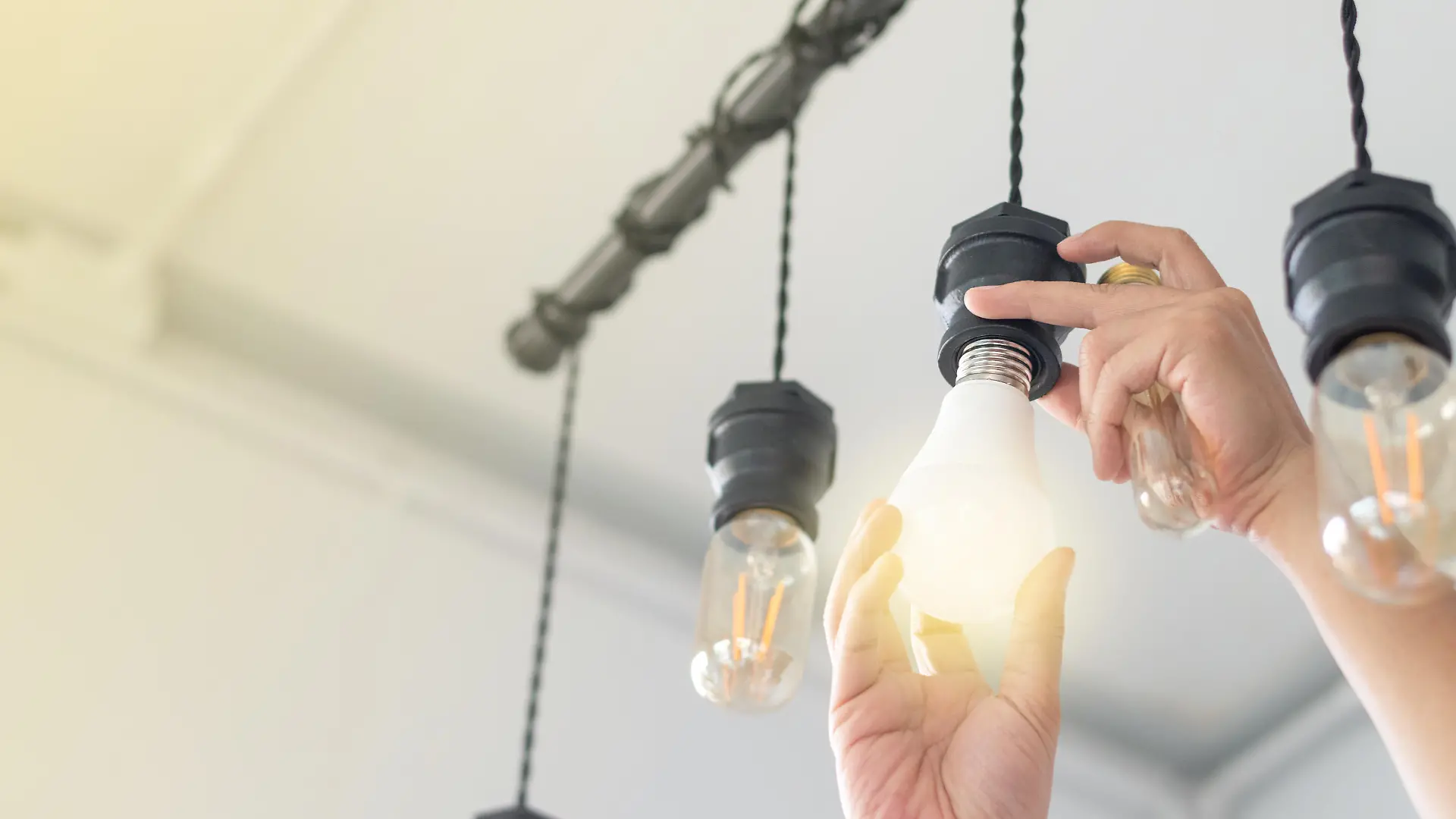 LED light Power saving concept. Asia man changing compact-fluorescent (CFL) bulbs with new bulb.