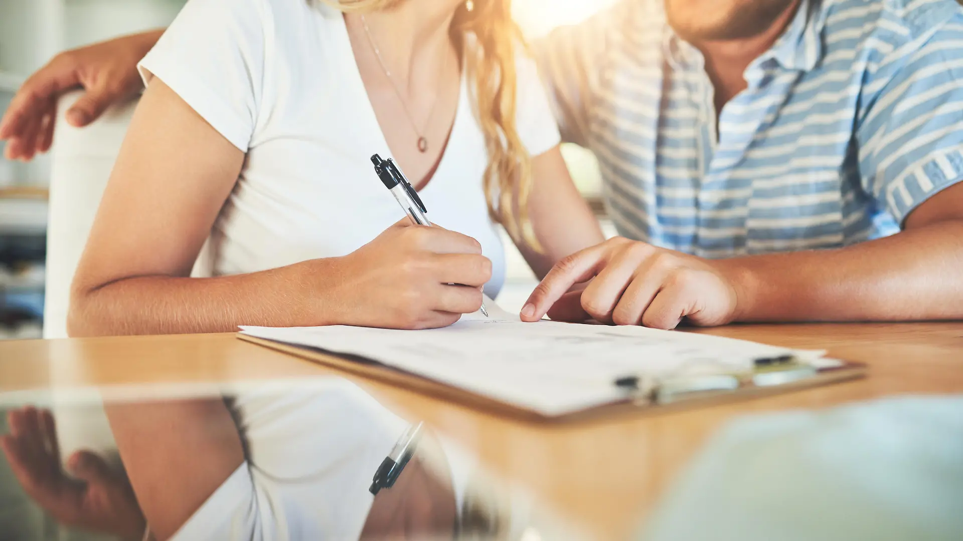 Shot of a young couple signing a document together at home