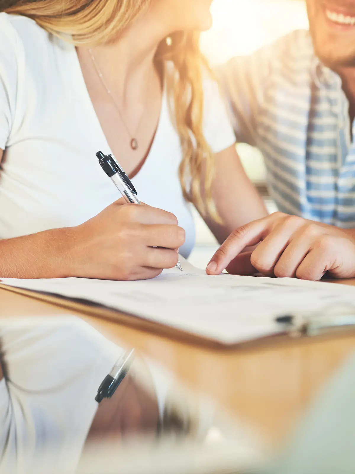 Shot of a young couple signing a document together at home