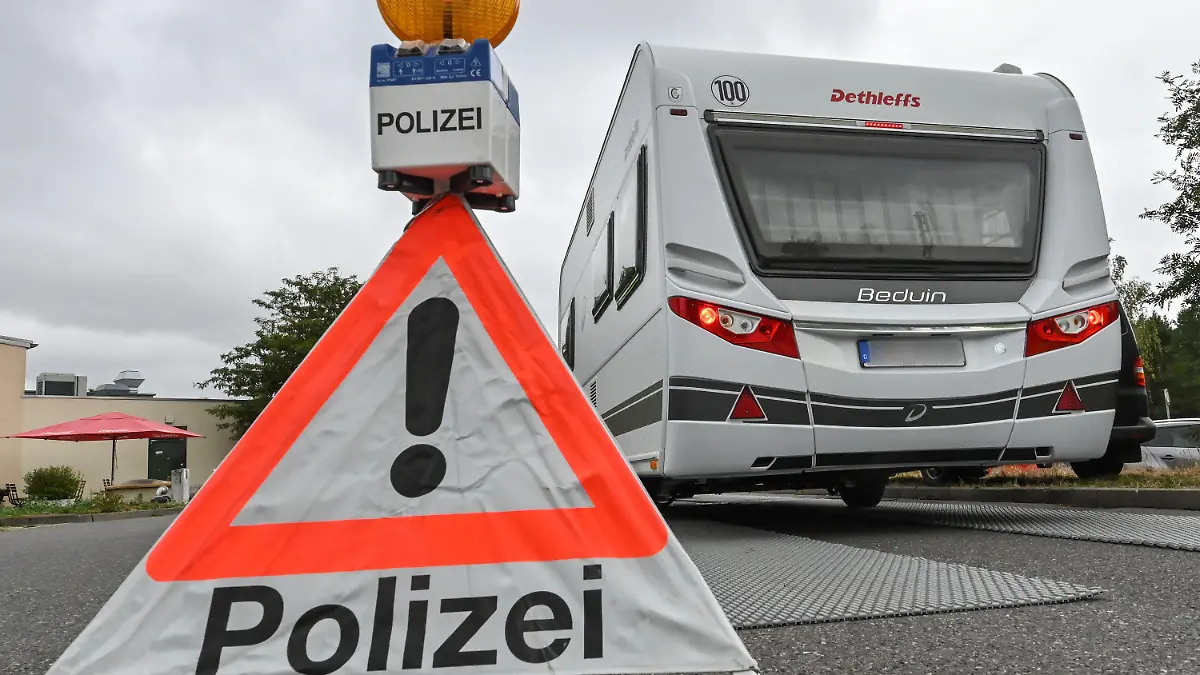 08.07.2022, Brandenburg, Duben: Bei einer Polizeikontrolle zum Reiseverkehr an der Tank- und Rastanlage Berstetal an der Autobahn 13 in Richtung Berlin muss ein Pkw mit Wohnanhänger über eine mobile Waage fahren. Die Ferien haben in vielen Ländern begonnen. Europaweit finden aus diesem Anlass verstärkte polizeiliche Kontrollen statt, an denen sich auch in diesem Jahr die Polizei des Landes Brandenburg beteiligt. Im Zeitraum vom 07. Juli bis 20. August 2022 wird die Polizei in Brandenburg verstärkt Verkehrskontrollen bei Wohnmobilen, Fahrzeugen mit Wohnanhängern sowie den Fahrzeugen, die deutlich als Ferienreiseverkehr erkennbar sind, durchführen. Foto: Patrick Pleul/dpa +++ dpa-Bildfunk +++