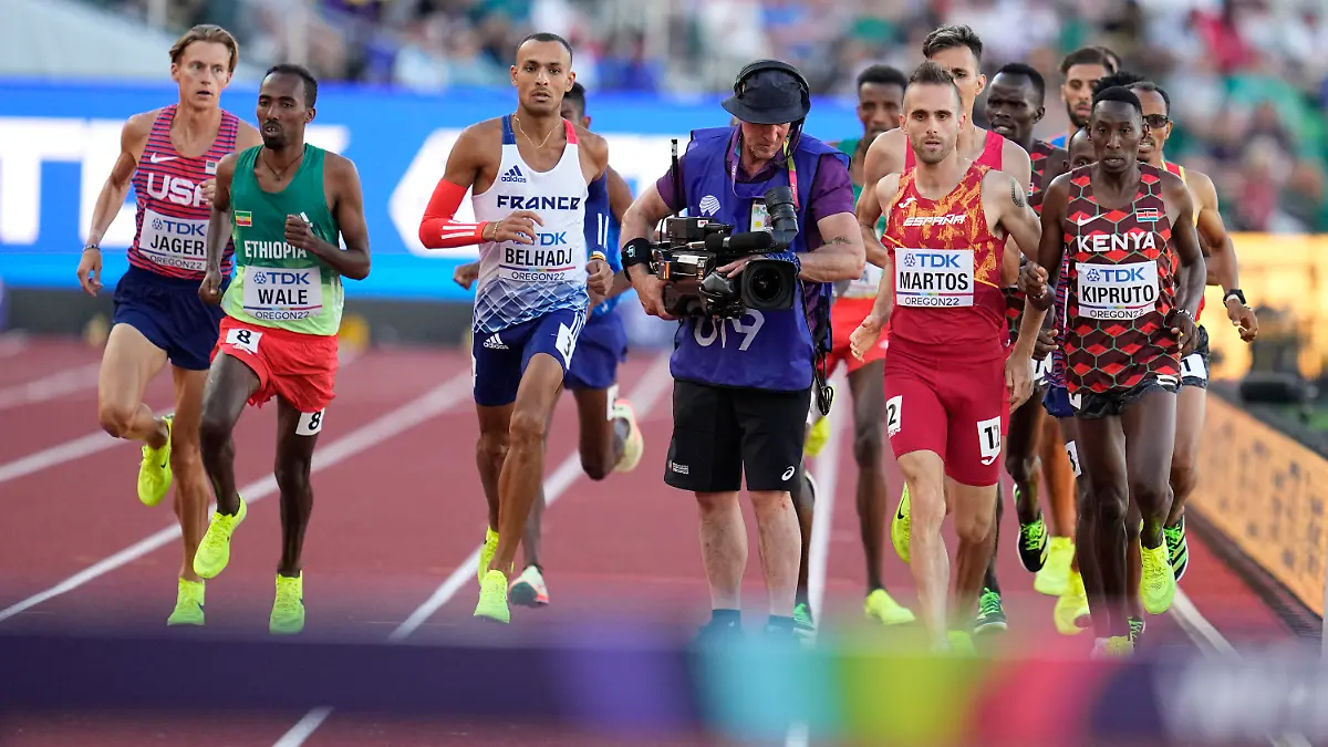 Men compete and move around a camera person on the track during the men's 3000-meter steeplechase final at the World Athletics Championships on Monday, July 18, 2022, in Eugene, Ore. (AP Photo/Ashley Landis)
