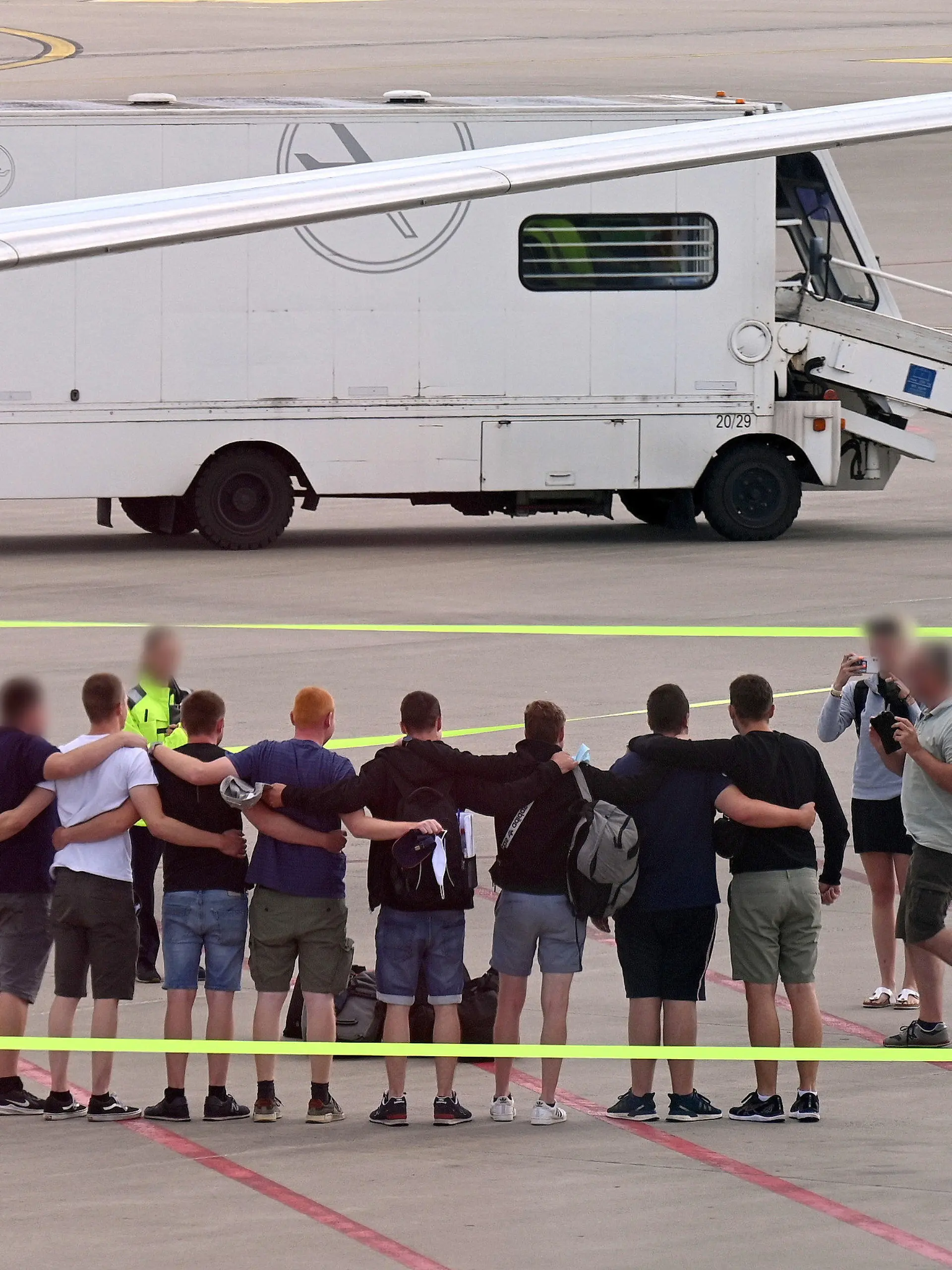 16.07.2022, Nordrhein-Westfalen, Münster: Die acht Männer, die auf Mallorca wegen Brandstiftung in Untersuchungshaft gesessen haben, stehen nach ihrer Ankunft in Deutschland auf dem Flugfeld auf dem Flughafen Münster-Osnabrück zusammen. Die acht Deutschen, die auf Mallorca der Brandstiftung verdächtigt werden und in U-Haft saßen, sind nach knapp zwei Monaten wieder zu Hause im Münsterland. (zu dpa: «Kegelbrüder wieder zu Hause - Mallorca-Alptraum ist aber nicht vorbei») Foto: Helmut P. Etzkorn/dpa - ACHTUNG: Person(en) wurde(n) aus rechtlichen Gründen gepixelt +++ dpa-Bildfunk +++