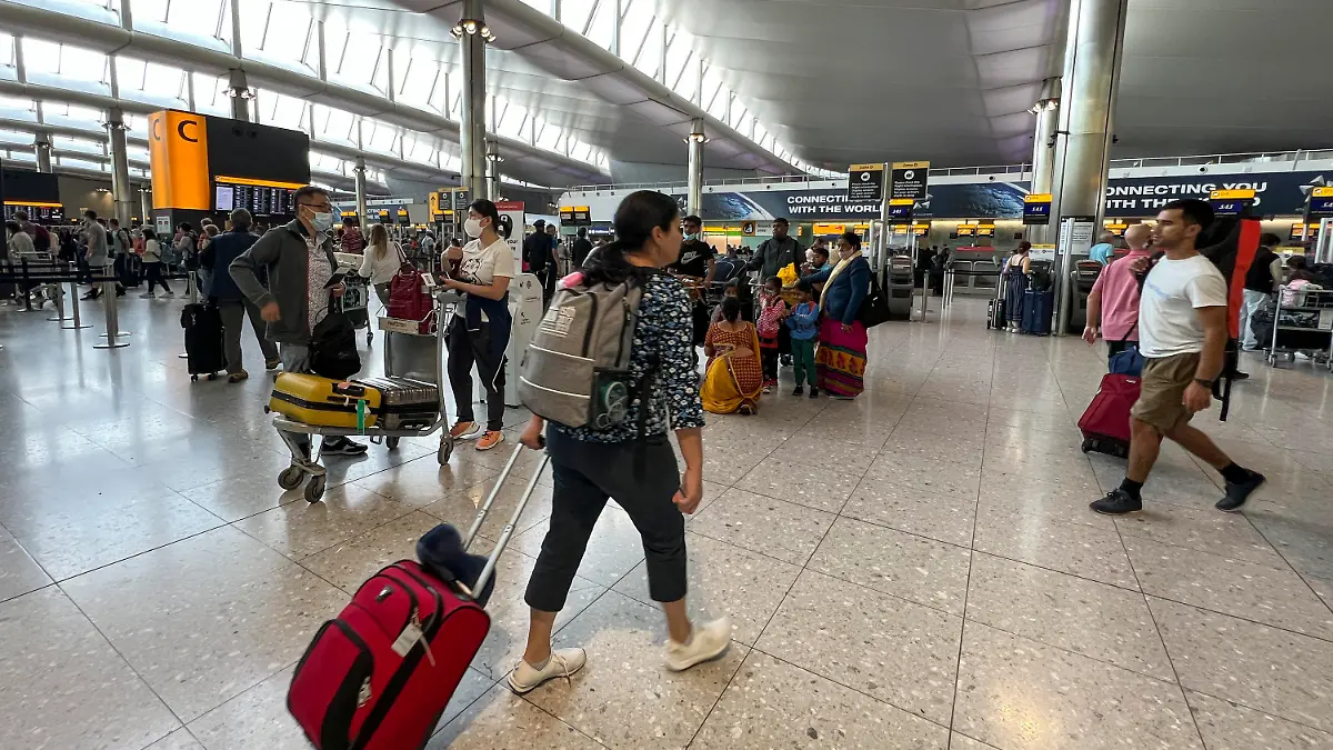 13.07.2022, Großbritannien, London: Reisende stehen am Flughafen Heathrow. Der Londoner Flughafen Heathrow hat ein Limit für die Zahl abreisender Passagiere für die Sommermonate eingeführt. Wie Geschäftsführer John Holland-Kaye am 12.07.22 in einem offenen Brief mitteilte, soll ab sofort bis zum 11. September eine Obergrenze von 100 000 Passagieren am Tag gelten. Foto: Alberto Pezzali/AP/dpa +++ dpa-Bildfunk +++