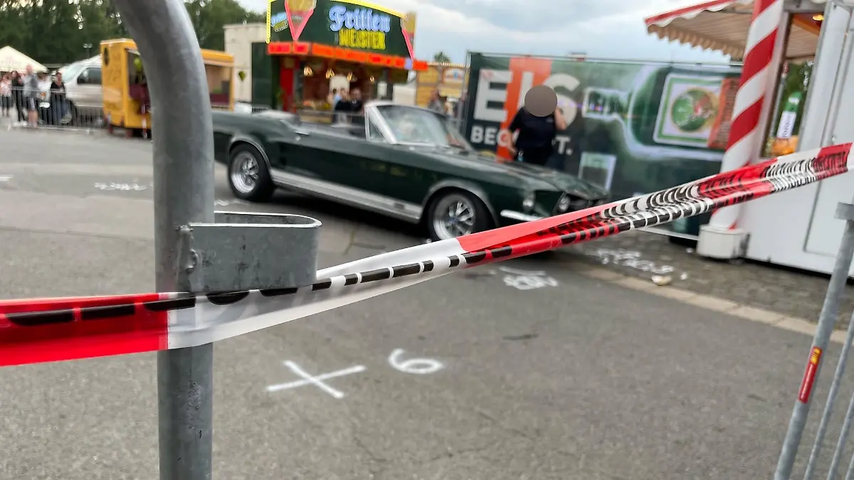 Im Hintergrund ist der Ford Mustang zu sehen, mit dem der Fahrer in die Menschenmenge gefahren sein ist.