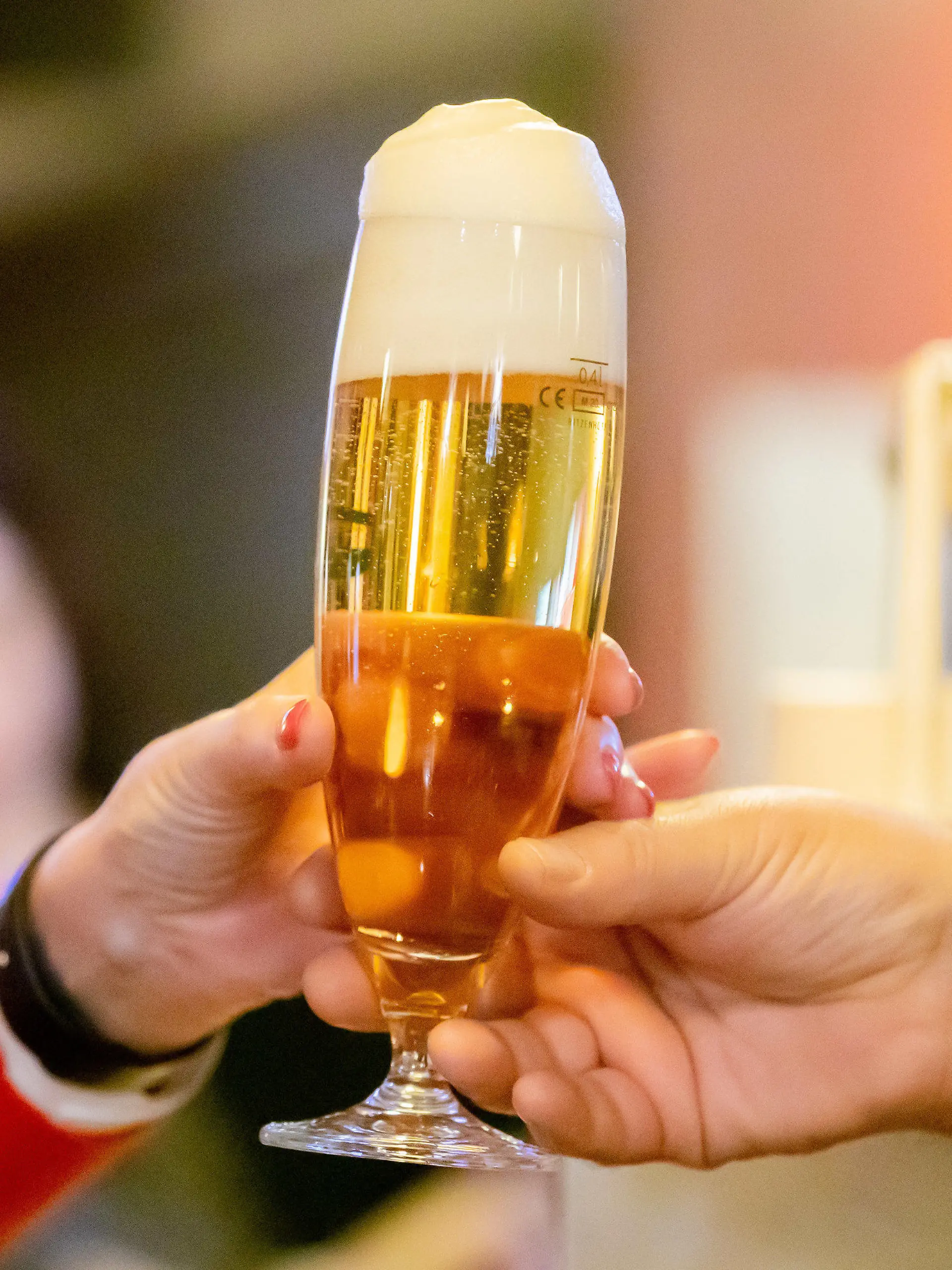 ARCHIV - 06.12.2021, Berlin: Ein Kneipenwirt reicht in einer Berliner Gaststätte einem Gast ein Bier. Menschen unter 40 Jahre sollten einer neuen Studie zufolge deutlich weniger Alkohol trinken als bisher angenommen. (zu dpa «Studie: Mehr als ein winziges Bier pro Tag schadet unter 40-Jährigen») Foto: Christoph Soeder/dpa +++ dpa-Bildfunk +++