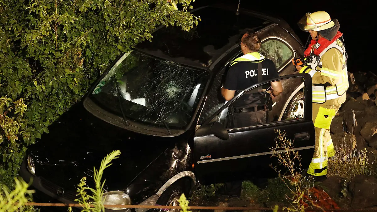 16.07.2022, Nordrhein-Westfalen, Düsseldorf: Polizisten und Feuerwehrleute arbeiten an einem geborgenen Opel Corsa. Eine 23 Jahre alte Fahrerin hat bei einem missglückten Wendemanöver versehentlich das falsche Pedal getreten. Das Auto sei vom Parkplatz direkt in den Rhein gefahren und komplett versunken. Foto: David Young/dpa +++ dpa-Bildfunk +++