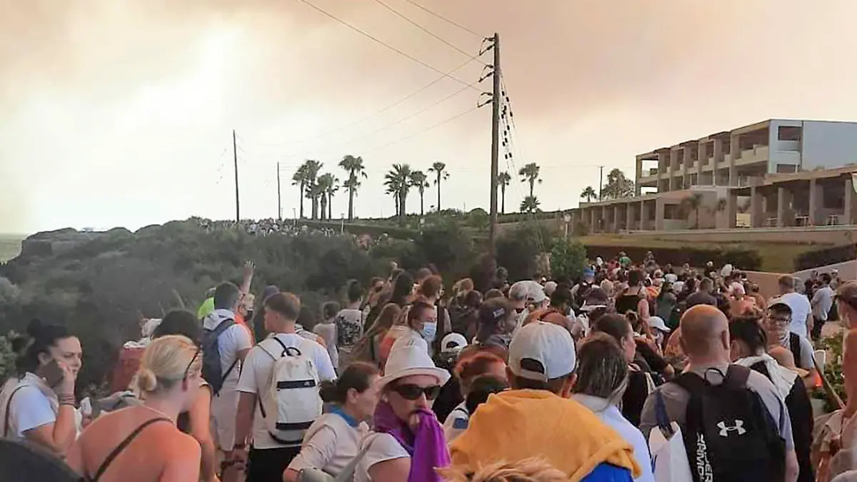 22.07.2023, Griechenland, Rhodos: Touristen werden während eines Waldbrandes auf der griechischen Insel Rhodos in SWicherheit gebracht. Ein Großbrand auf der griechischen Insel Rhodos, der bereits den fünften Tag andauert, hat die Behörden gezwungen, die Evakuierung von vier Orten, darunter zwei Badeorte, anzuordnen. Foto: Uncredited/Rhodes.Rodos/AP/dpa +++ dpa-Bildfunk +++