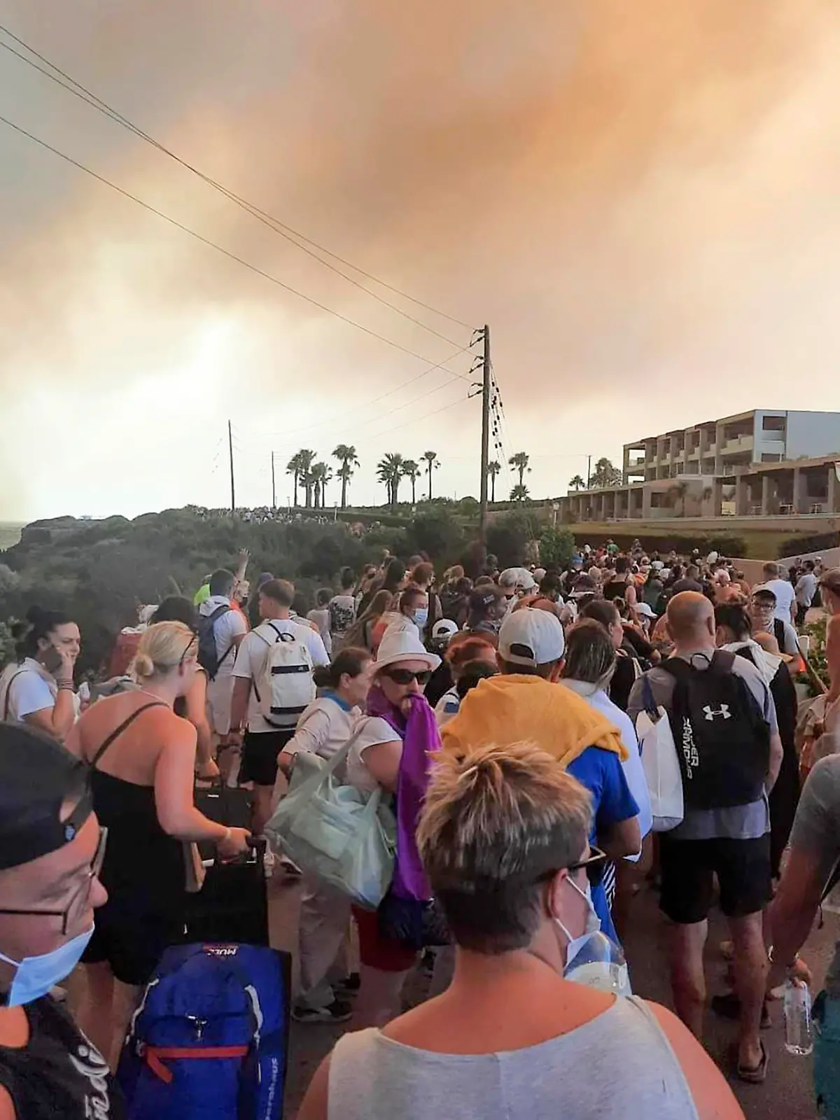 22.07.2023, Griechenland, Rhodos: Touristen werden während eines Waldbrandes auf der griechischen Insel Rhodos in SWicherheit gebracht. Ein Großbrand auf der griechischen Insel Rhodos, der bereits den fünften Tag andauert, hat die Behörden gezwungen, die Evakuierung von vier Orten, darunter zwei Badeorte, anzuordnen. Foto: Uncredited/Rhodes.Rodos/AP/dpa +++ dpa-Bildfunk +++