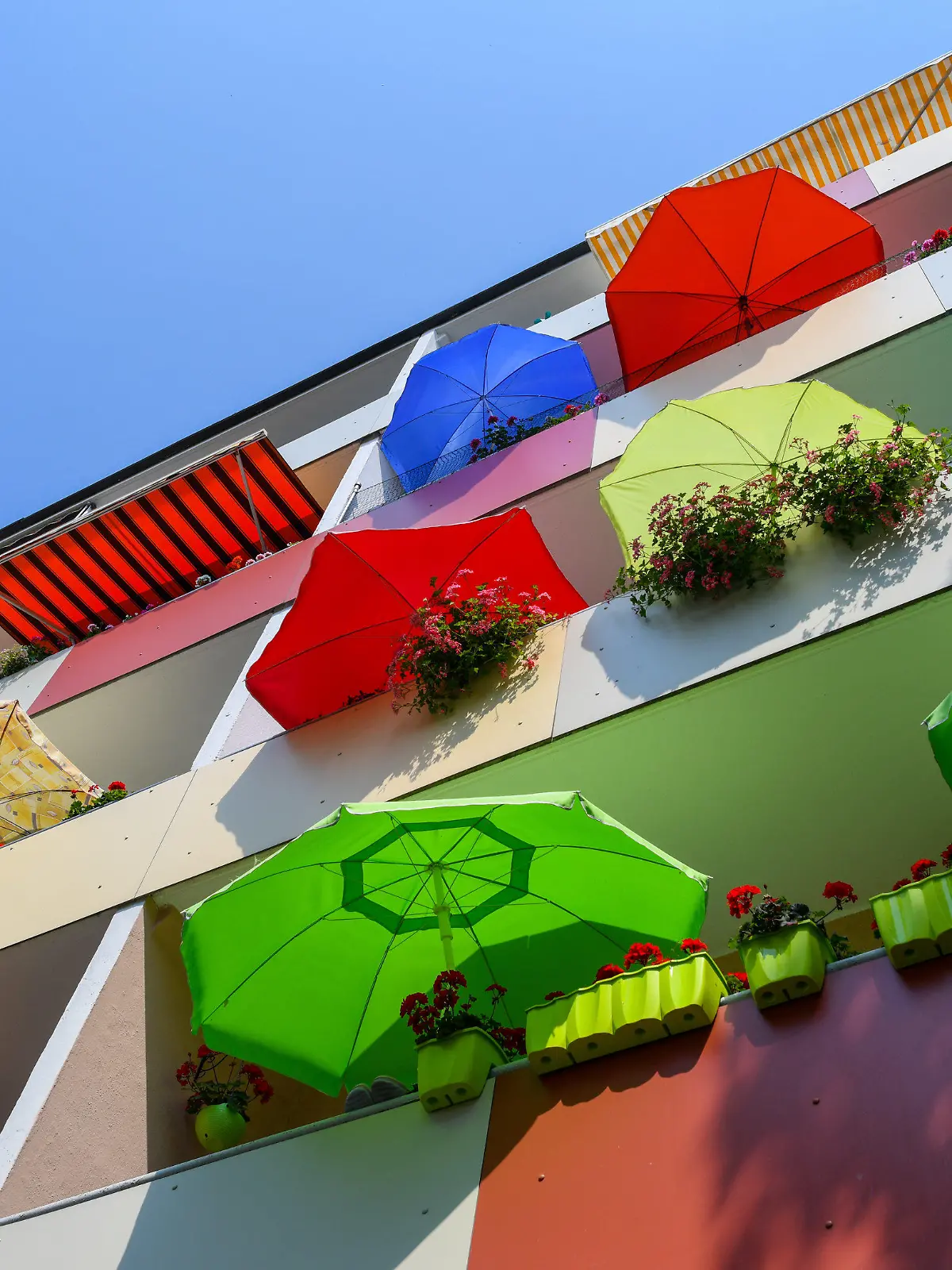 20.07.2018, Brandenburg, Frankfurt (Oder): Bunte Sonnenschirme leuchten in der Mittagssonne auf Balkonen eines Mehrfamilienhauses. Foto: Patrick Pleul/dpa-Zentralbild/dpa +++ dpa-Bildfunk +++