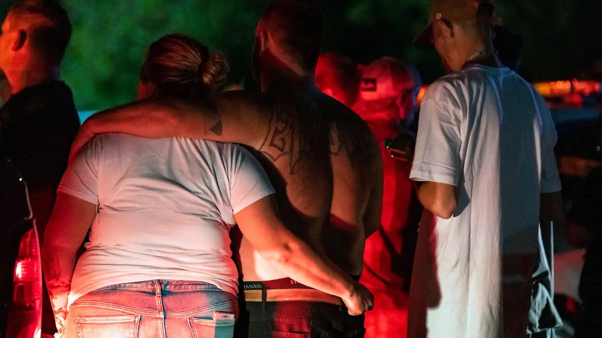 Family and friends embrace each other as Indianapolis Metropolitan Police Department investigators search for a father and three children Tuesday, July 12, 2022, on Bluff Road in Indianapolis. The bodies of a man and three young children were found in an Indianapolis pond amid a search for a father and his kids who had been missing since last week, authorities said Wednesday. (Grace Hollars/The Indianapolis Star via AP)