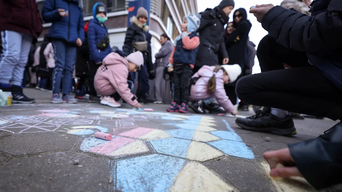 ARCHIV - 09.03.2022, Hamburg: Kinder, die mit ihren Angehörigen aus der Ukraine geflohen sind, malen mit Kreide auf den Boden, während ihre Familien und weiterer ukrainische Flüchtlinge vor der Zentralen Ausländerbehörde mit der neuen Registrierungsstelle im Amt für Migration an der Hammer Straße warten. (zu dpa «Hamburg stellt sich auf Tausende neue Schüler aus der Ukraine ein») Foto: Christian Charisius/dpa +++ dpa-Bildfunk +++