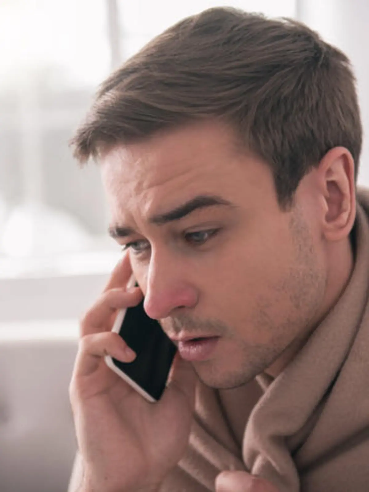 Phone conversation. Portrait of a nice handsome man pressing the phone to his ear while having a phone conversation