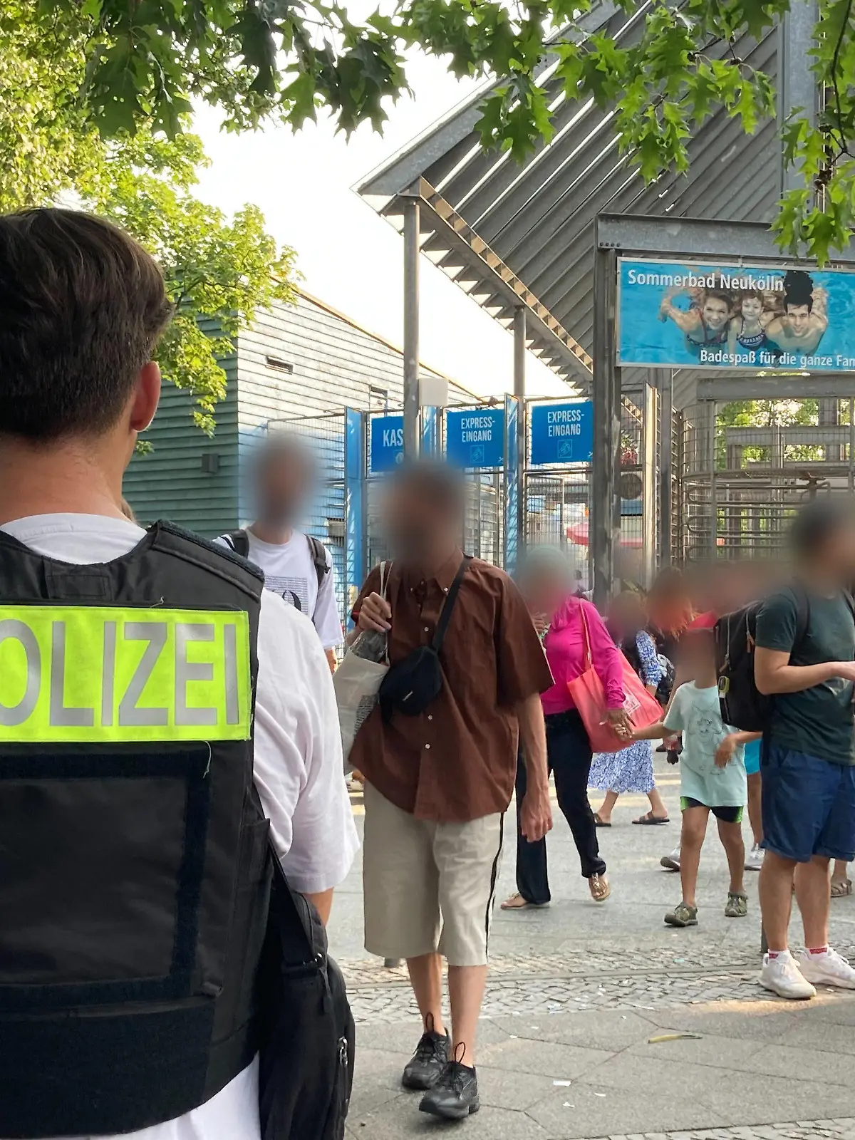 09.07.2023, Berlin: Polizisten stehen vor dem Eingang des Sommerbad in Neukölln. Das Berliner Freibad wird wegen seiner Lage am Columbiadamm auch Columbiabad genannt. Zum wiederholten Male war ein Berliner Freibad wegen Rangeleien und renitenter Besucher frühzeitig geschlossen und geräumt worden. Foto: Carioline Bock/dpa - ACHTUNG: Person(en) wurde(n) aus rechtlichen Gründen gepixelt +++ dpa-Bildfunk +++