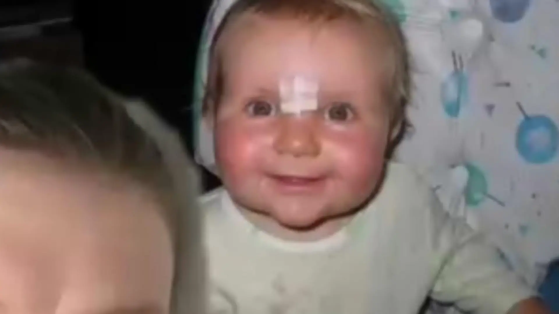 Baby mit Pflaster am Kopf.