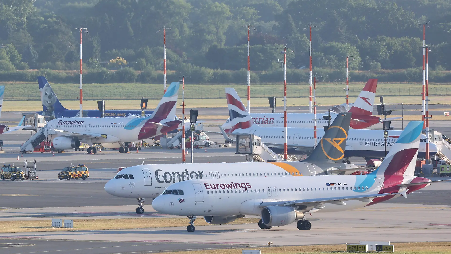 02.07.2022, Hamburg: Flugzeuge stehen am Hamburger Flughafen. Jeweils eine Maschine der Fluggesellschaften Eurowings und Condor rollen zu Startbahn. In Schleswig-Holstein haben die Ferien begonnen. Foto: Bodo Marks/dpa +++ dpa-Bildfunk +++