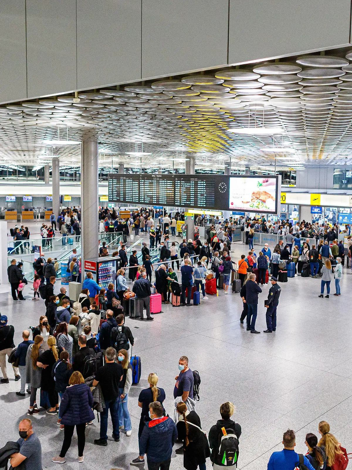 02.10.2021, Niedersachsen, Langenhagen: Reisende warten im Terminal C vom Flughafen Hannover-Langenhagen auf die Sicherheitsabfertigung. Weil der von der Bundespolizei für die Abfertigungs-Kontrollen beauftragte Dienstleister massive Personalprobleme hat, kam es zuletzt zu großen Wartezeiten, teilweise verpassten Reisende deswegen ihre Flüge. Foto: Michael Matthey/dpa +++ dpa-Bildfunk +++