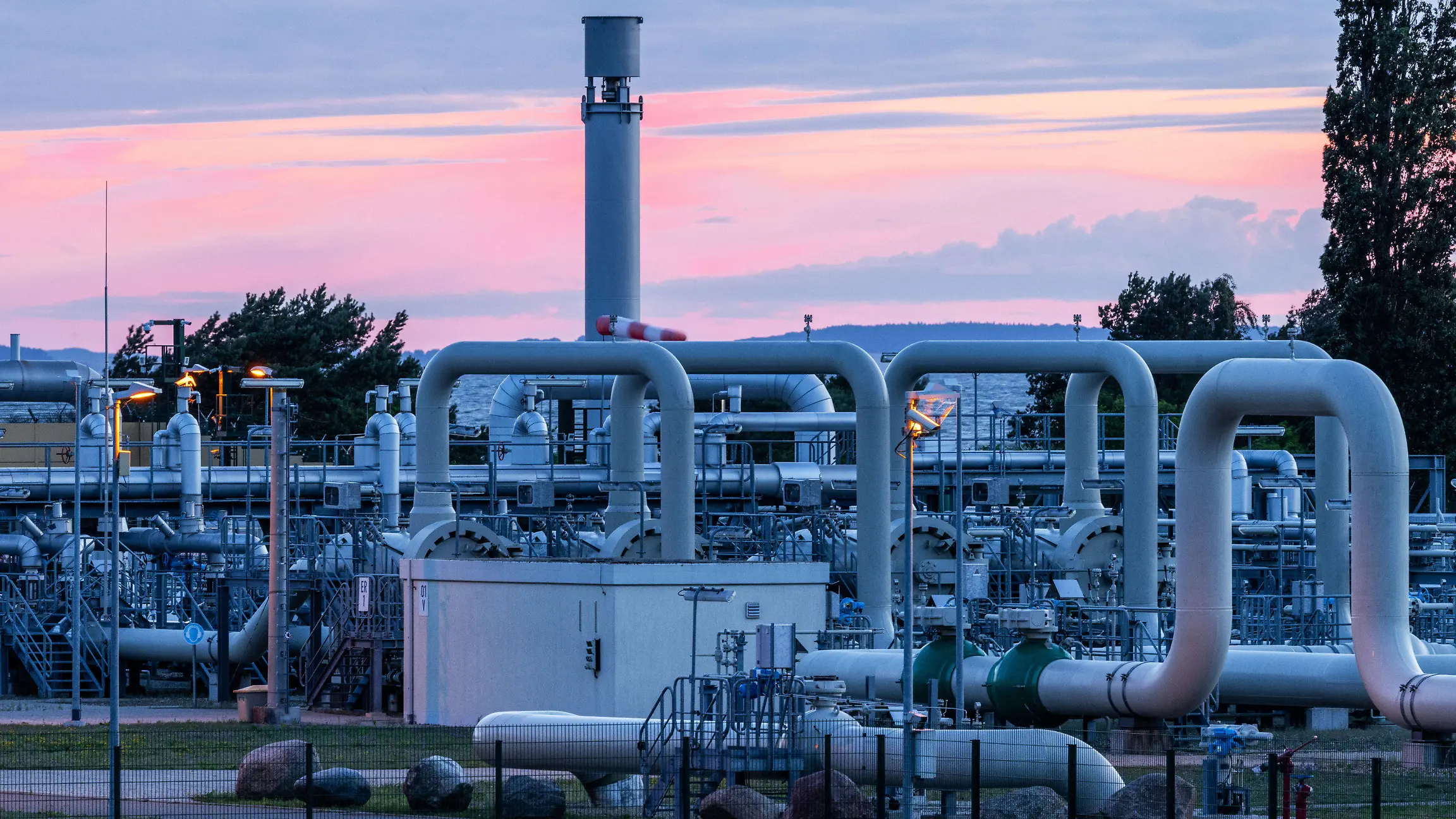 11.07.2022, Mecklenburg-Vorpommern, Lubmin: Rohrsysteme und Absperrvorrichtungen in der Gasempfangsstation der Ostseepipeline Nord Stream 1 und der Übernahmestation der Ferngasleitung OPAL (Ostsee-Pipeline-Anbindungsleitung) sind vor Sonnenaufgang zu sehen. Die Ostsee-Pipeline Nord Stream 1, durch die seit 2011 russisches Erdgas nach Deutschland fließt, wird wegen planungsmäßiger Wartungsarbeiten für etwa zehn Tage abgeschaltet. Foto: Jens Büttner/dpa +++ dpa-Bildfunk +++