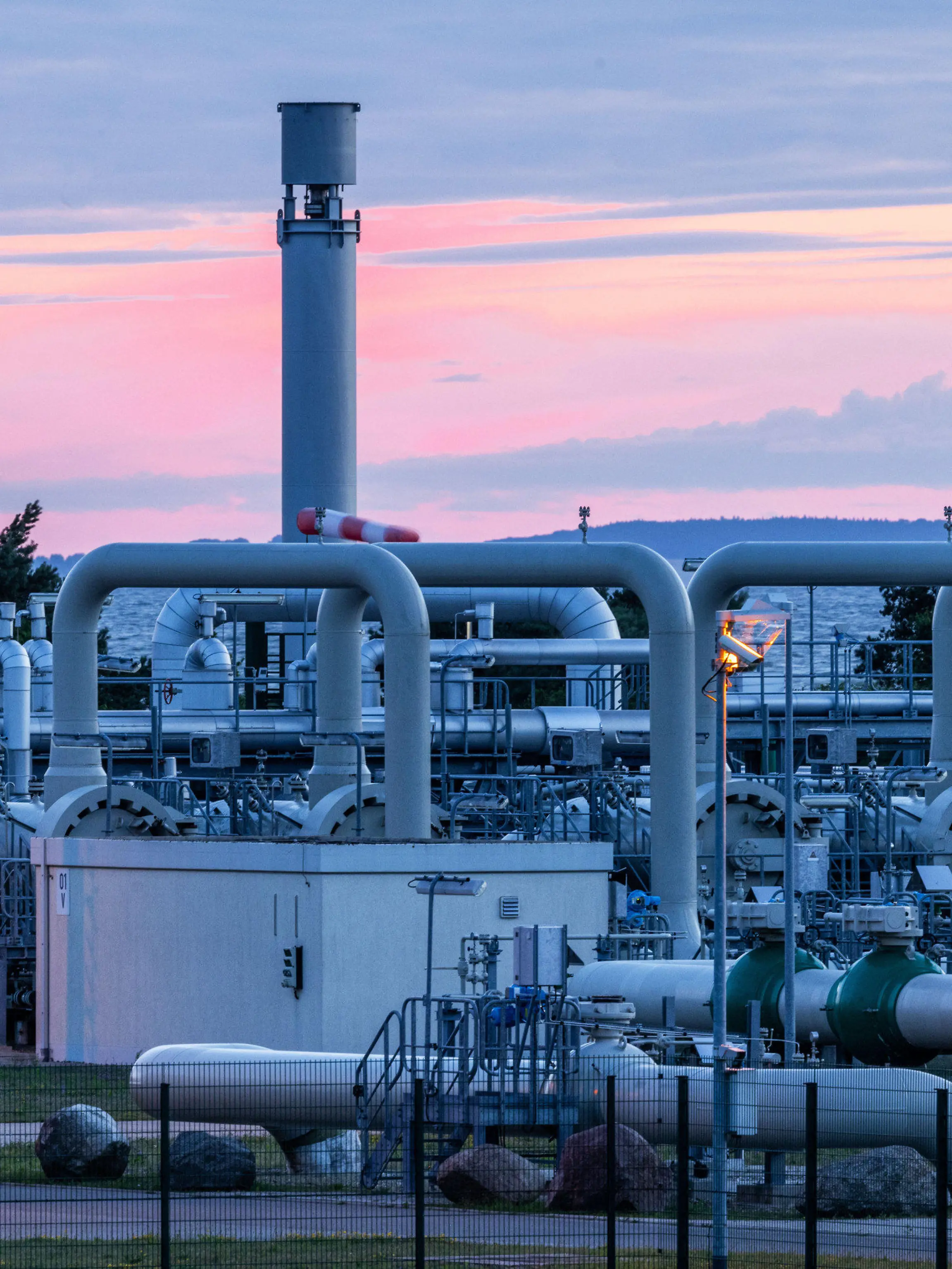 11.07.2022, Mecklenburg-Vorpommern, Lubmin: Rohrsysteme und Absperrvorrichtungen in der Gasempfangsstation der Ostseepipeline Nord Stream 1 und der Übernahmestation der Ferngasleitung OPAL (Ostsee-Pipeline-Anbindungsleitung) sind vor Sonnenaufgang zu sehen. Die Ostsee-Pipeline Nord Stream 1, durch die seit 2011 russisches Erdgas nach Deutschland fließt, wird wegen planungsmäßiger Wartungsarbeiten für etwa zehn Tage abgeschaltet. Foto: Jens Büttner/dpa +++ dpa-Bildfunk +++