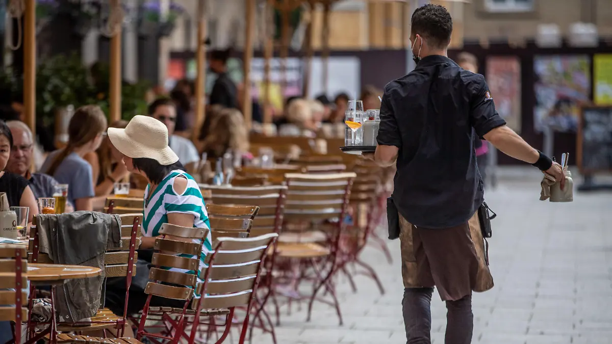 ARCHIV - 20.08.2021, Baden-Württemberg, Stuttgart: Eine Servicekraft läuft im Außenbereich eines Restaurants an Gästen vorbei. Experten im Gastgewerbe und der Landwirtschaft sehen die Ausstattung mit Saisonkräften in Sachsen-Anhalt in den jeweiligen Branchen verbessert. (zu dpa: «Verbände sehen Situation mit Saisonkräften verbessert») Foto: Christoph Schmidt/dpa +++ dpa-Bildfunk +++