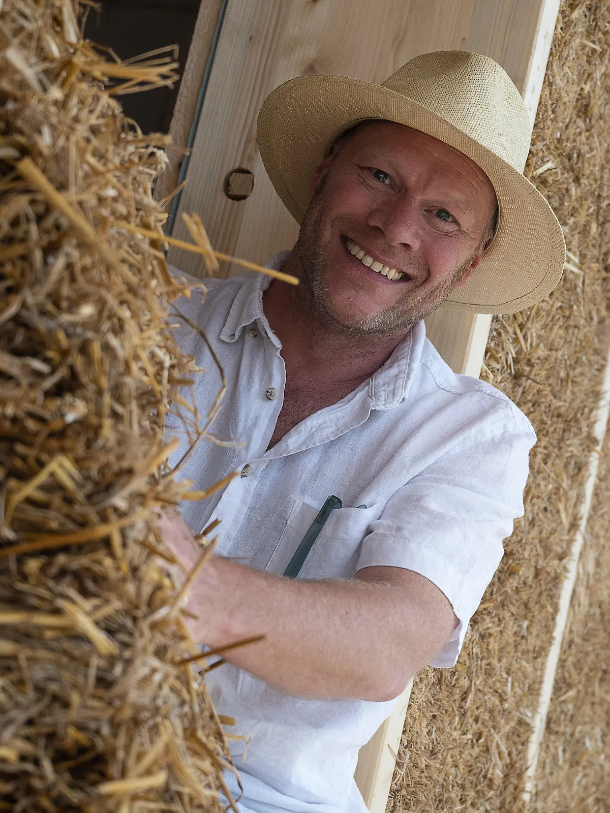 PRODUKTION - 28.06.2022, Hessen, Kassel: Christoph Harney, Architekt, sitzt in einem Neubauprojekt eines Mehrfamilienhauses der Genossenschaft "Kassel im Wandel". Die Genossenschaft aus Kassel setzt auf ökologischen Baustoff. Den Strohballenbau gibt es schon seit Ende des 19. Jahrhunderts. Doch lange Zeit war er wenig populär. Dabei sind Strohballen als Dämmstoff günstig, nachhaltig und energetisch hochwertig. Foto: Swen Pförtner/dpa +++ dpa-Bildfunk +++