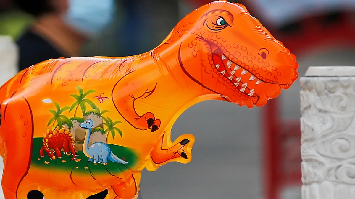 A child wearing a face mask to help curb the spread of the coronavirus holds a dinosaur shaped balloon walks at a public park in Beijing, Sunday, May 16, 2021. (AP Photo/Andy Wong)