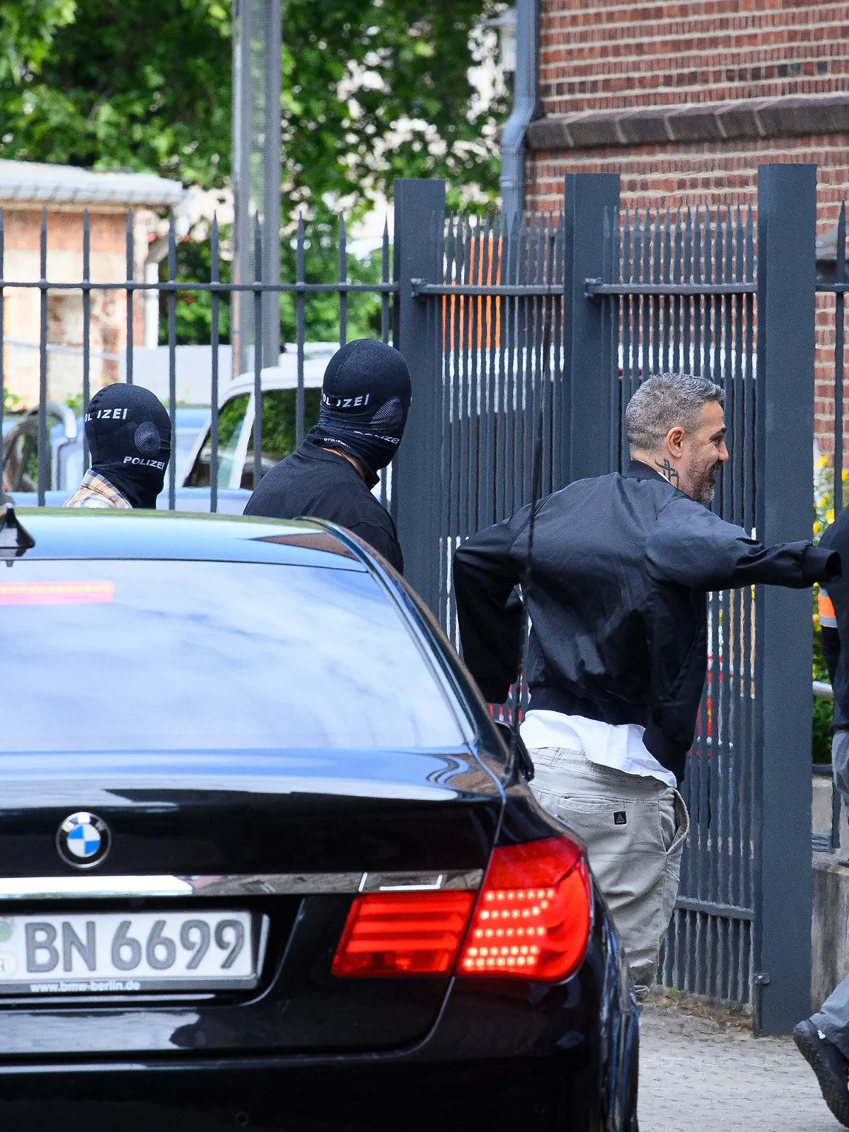 15.06.2022, Brandenburg, Potsdam: Der Rapper Bushido (M) kommt unter Polizeischutz zum Potsdamer Amtsgericht. Die gemeinsame Immobilie des Rappers Bushido und seinem früheren Geschäftspartner soll am Vormittag in Kleinmachnow (Potsdam-Mittelmark) zwangsversteigert werden. In dem Prozess mit Bushido als Nebenkläger und Zeuge steht sein früherer Partner, ein Berliner Clanchef, gemeinsam mit drei seiner Brüder vor Gericht. Foto: Soeren Stache/dpa +++ dpa-Bildfunk +++