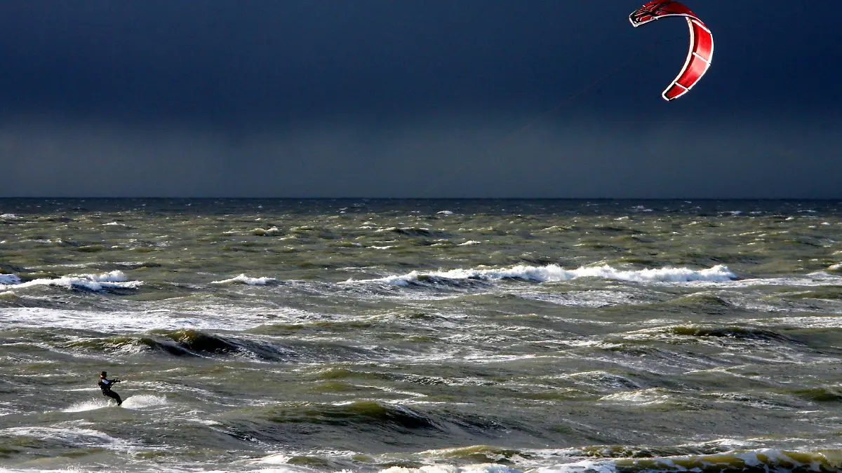 Vor dem dunklen Himmel einer Regenfront nutzt am Montag (03.03.2008) vor Westerland auf Sylt ein Kitesurfer den starken Wind für seinen Sport. Auch in den kommenden Tagen ist mit stürmischem Wetter und Regen- sowie Graupelschauern zu rechnen. Die Temperaturen steigen kaum über 5 Grad. Foto: Carsten Rehder dpa/lno   +++(c) dpa - Bildfunk+++
