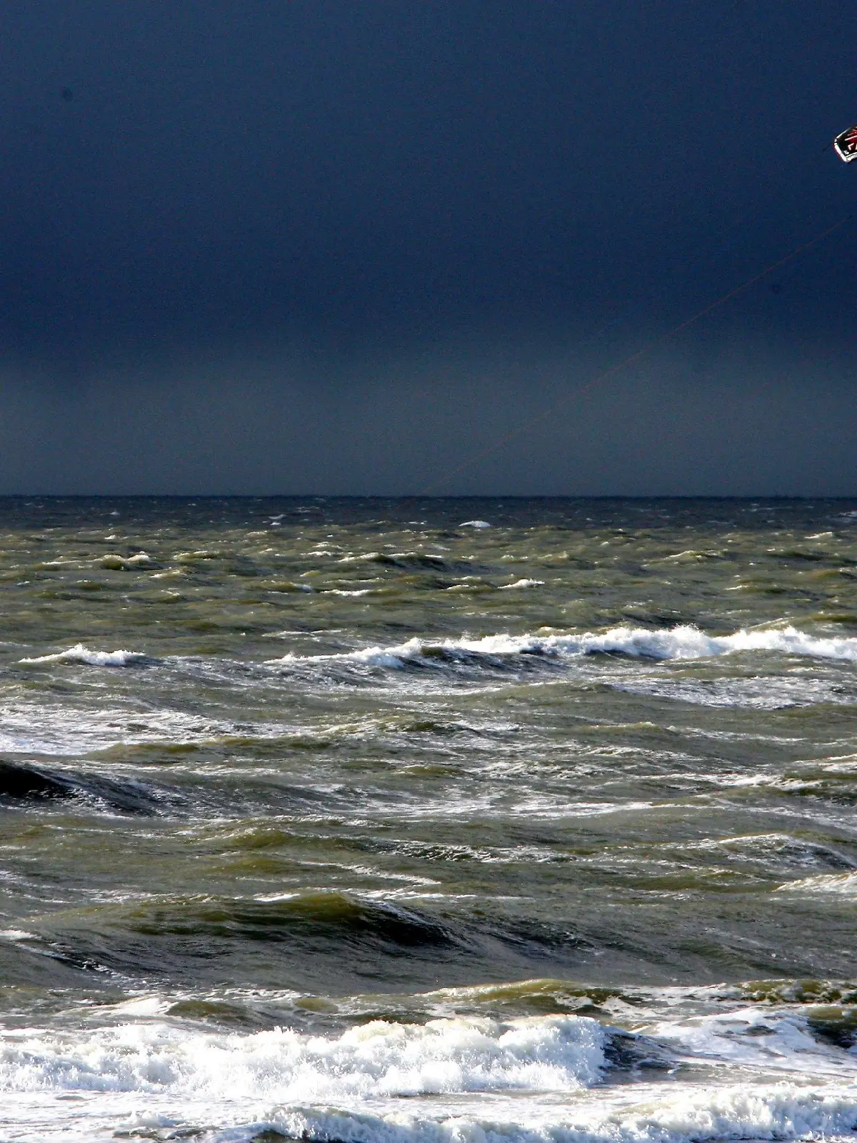 Vor dem dunklen Himmel einer Regenfront nutzt am Montag (03.03.2008) vor Westerland auf Sylt ein Kitesurfer den starken Wind für seinen Sport. Auch in den kommenden Tagen ist mit stürmischem Wetter und Regen- sowie Graupelschauern zu rechnen. Die Temperaturen steigen kaum über 5 Grad. Foto: Carsten Rehder dpa/lno   +++(c) dpa - Bildfunk+++