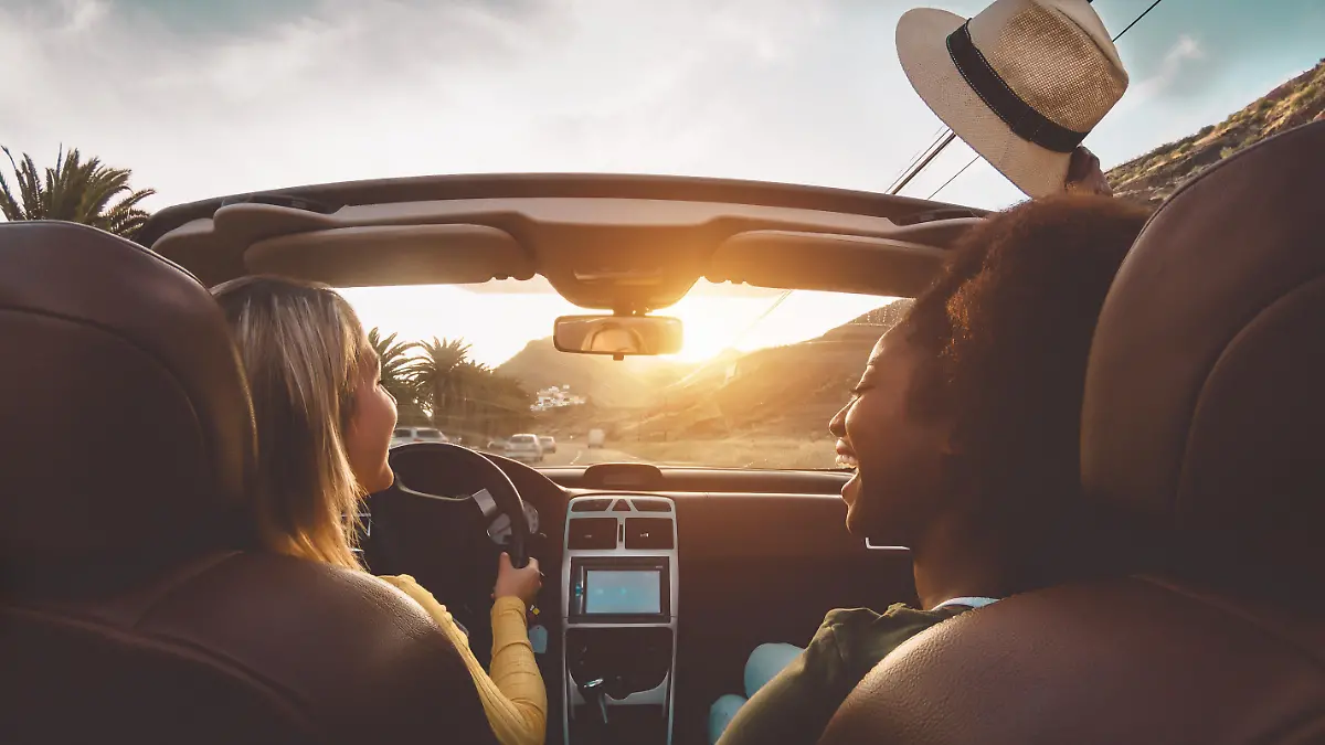 Happy girls doing road trip in tropical city - Travel people having fun driving in trendy convertible car discovering new places - Friendship and youth girlfriends vacation lifestyle concept