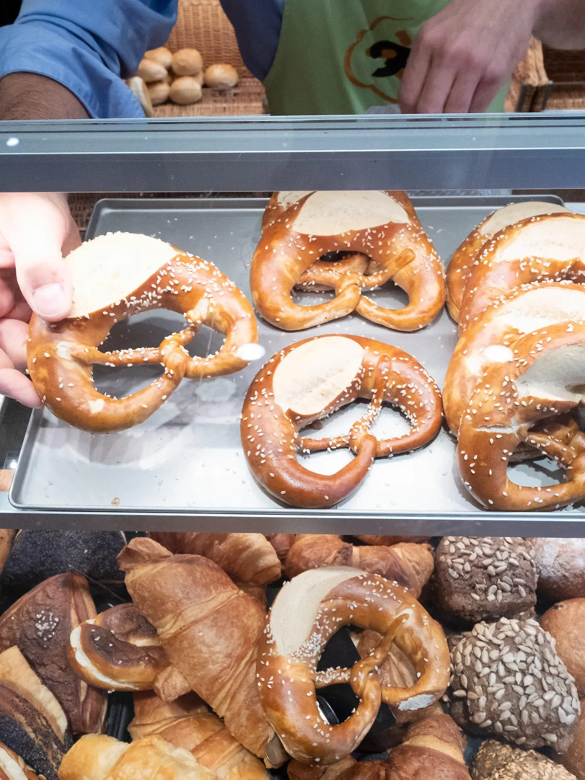 ARCHIV - 17.10.2019, Baden-Württemberg, Stuttgart: Ein Hand nimmt in einer Bäckerei eine Brezel aus einer Auslage. (zu dpa: «Gratisbrezeln für Pendler kosteten das Land fast 60 000 Euro») Foto: Bernd Weißbrod/dpa +++ dpa-Bildfunk +++