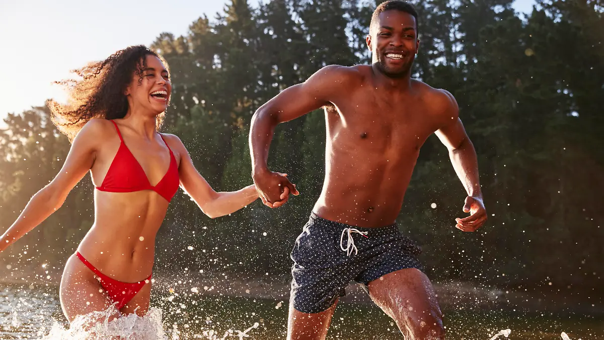 Young mixed race couple running and splashing in a lake