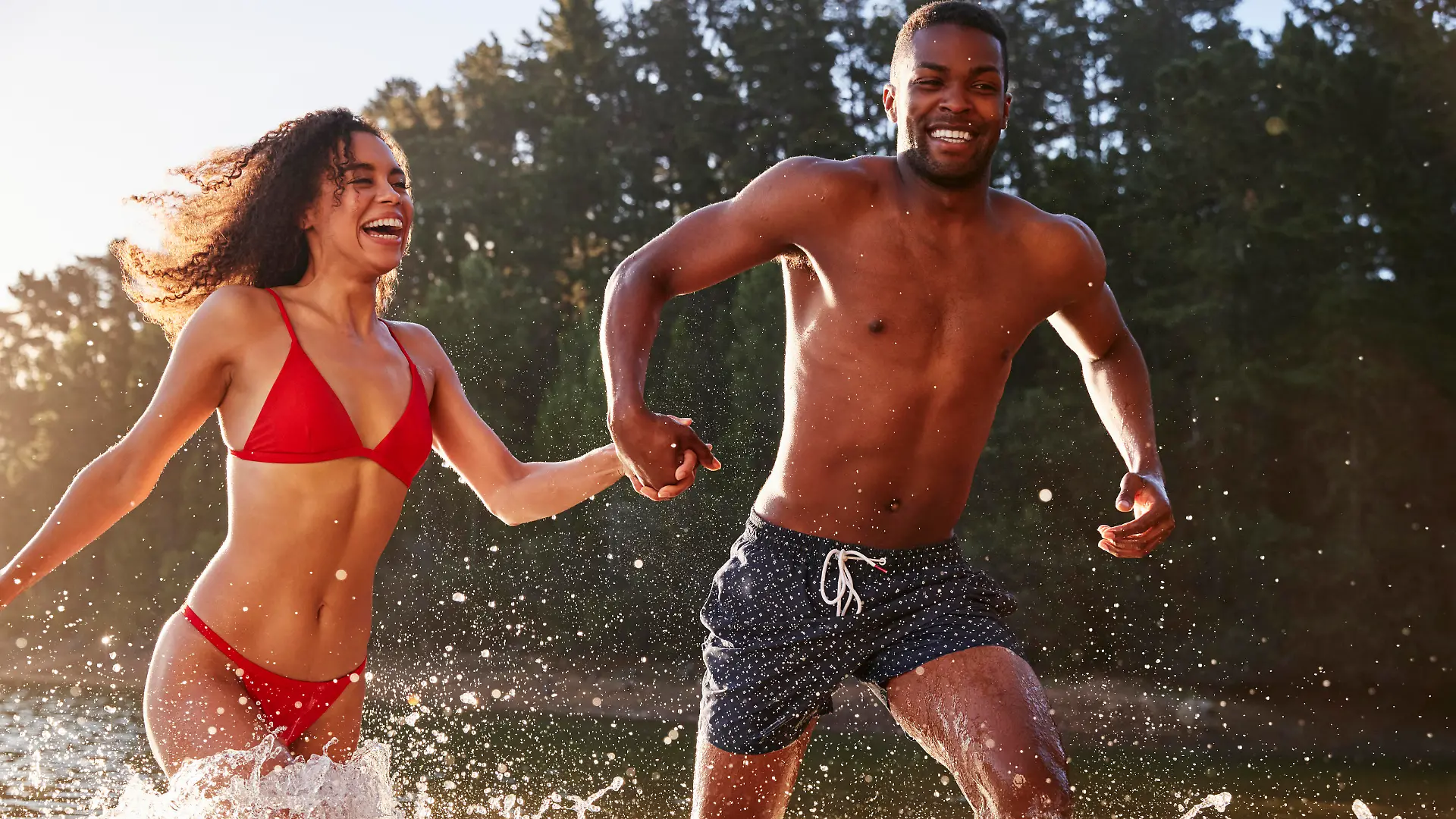 Young mixed race couple running and splashing in a lake