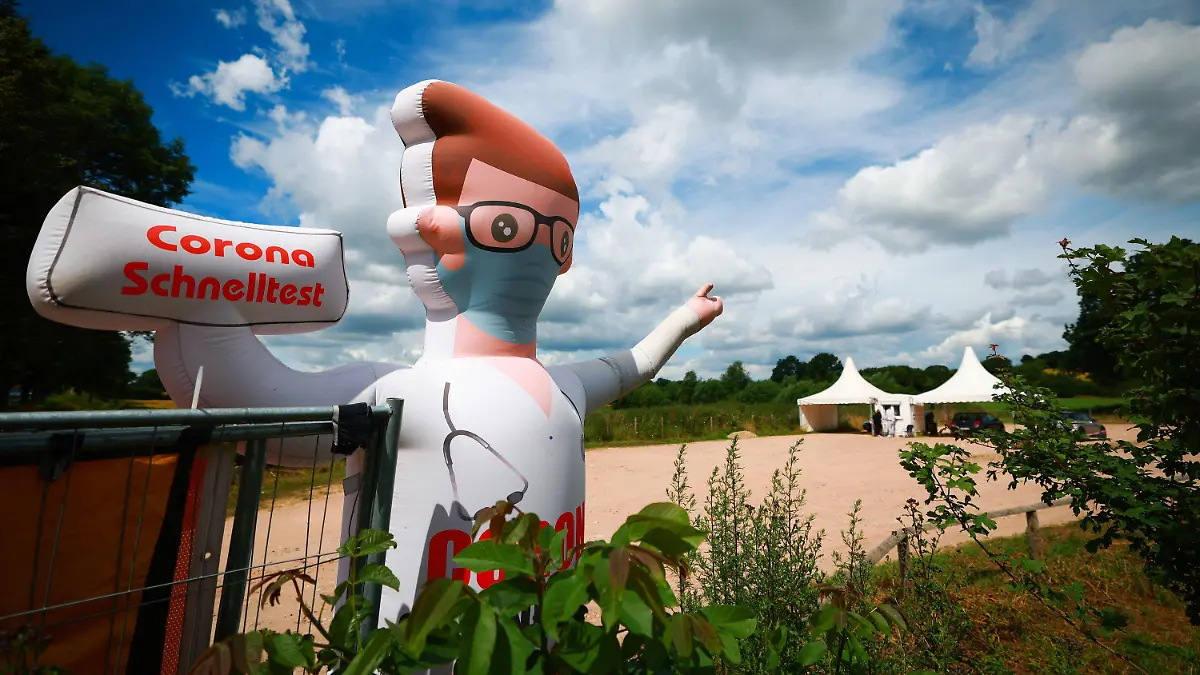 04.07.2022, Schleswig-Holstein, Hemmelsdorf: Eine aufblasbare Werbefigur weist den Weg zu einem Drive-In Testcenter für Corona Schnelltests bei Timmendorfer Strand. Wegen Corona-Fällen in der Belegschaft ist die Lage in den Krankenhäusern in Schleswig-Holstein weiter angespannt. Foto: Christian Charisius/dpa +++ dpa-Bildfunk +++