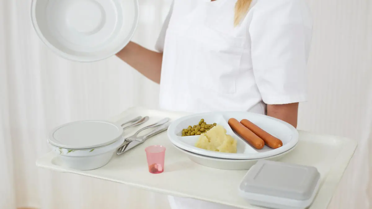 Friendly nurse is serving hospital food