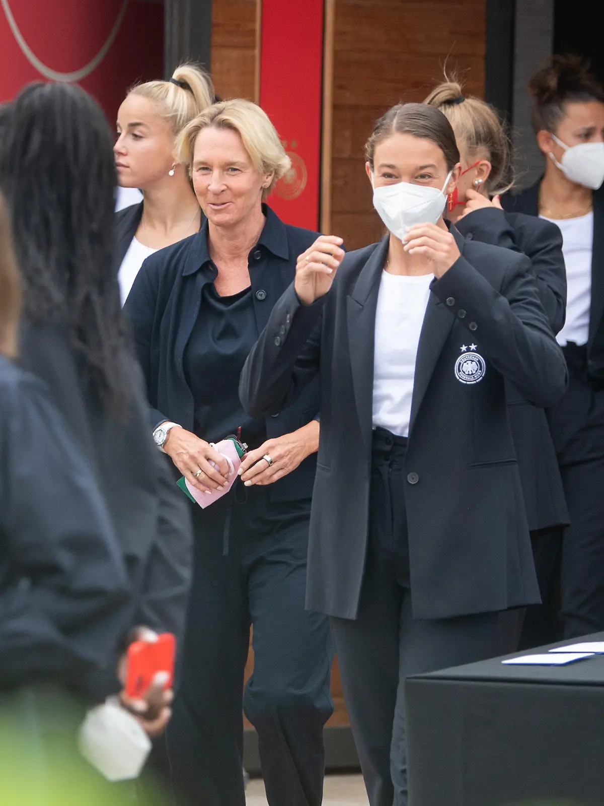 03.07.2022, Großbritannien, London: Fußball: Nationalmannschaft, Frauen, EM 2022: Bundestrainer Martina Voss-Tecklenburg (M) steht zwischen ihren Spielerinnen. Foto: Sebastian Gollnow/dpa - WICHTIGER HINWEIS: Gemäß den Vorgaben der DFL Deutsche Fußball Liga bzw. des DFB Deutscher Fußball-Bund ist es untersagt, in dem Stadion und/oder vom Spiel angefertigte Fotoaufnahmen in Form von Sequenzbildern und/oder videoähnlichen Fotostrecken zu verwerten bzw. verwerten zu lassen. +++ dpa-Bildfunk +++
