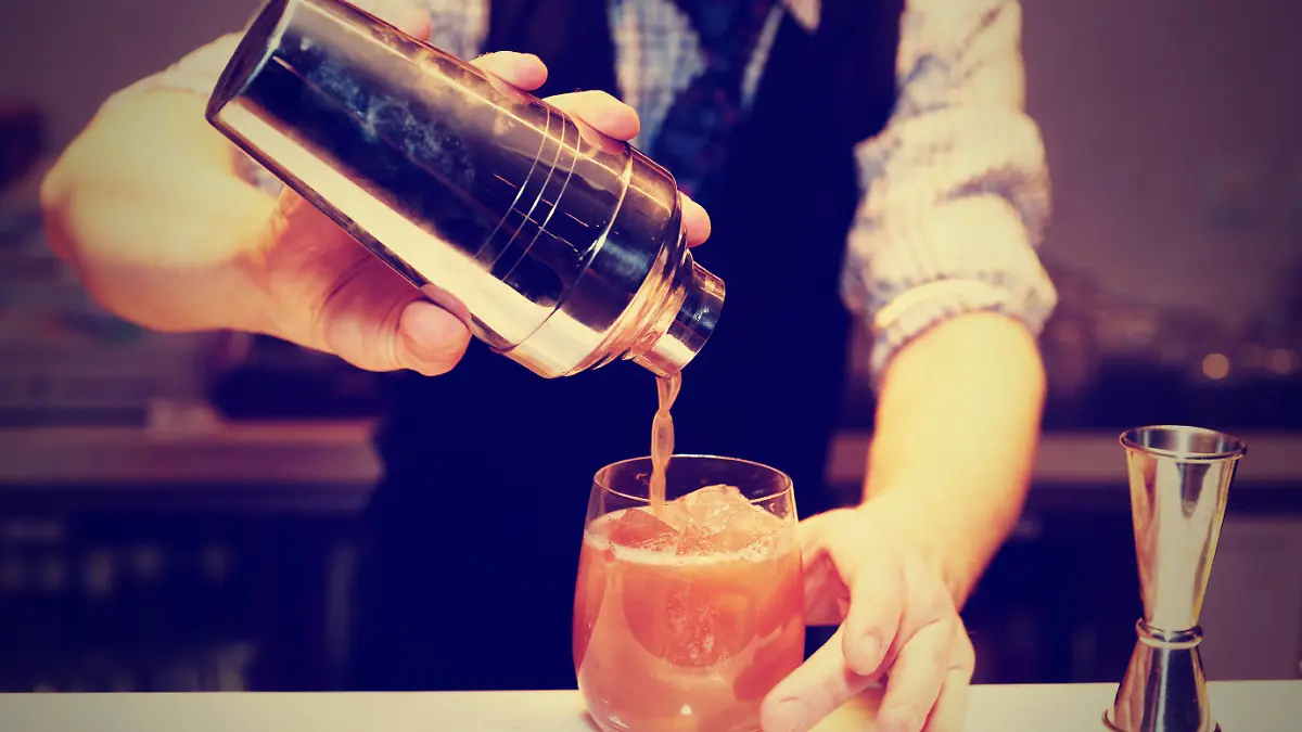 Bartender is making cocktail at bar counter, toned image