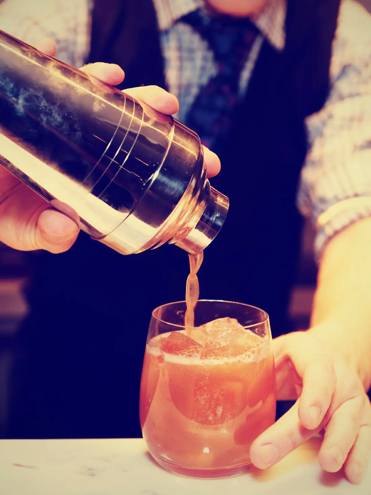 Bartender is making cocktail at bar counter, toned image
