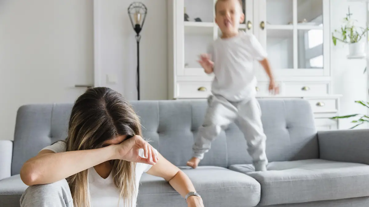 Hyperactive child and his tired and sad mother at home