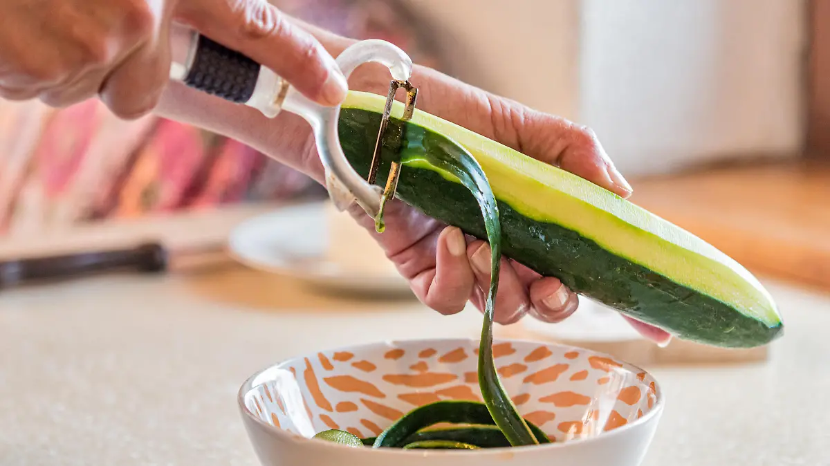 Woman Hands Peeling Cucumber for Making Fresh Mediterranean Salad