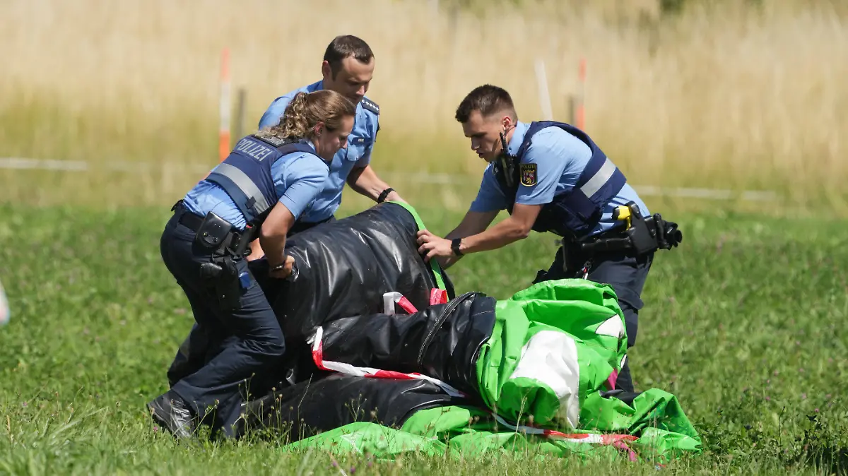 03.07.2022, Rheinland-Pfalz, Gondershausen: Polizeibeamte transportieren die Hülle einer Hüpfburg ab. Das Spielgerät war bei einem Fest auf dem Sportplatz von Gondershausen von einer Windböe erfasst und mindestens vier Meter in die Höhe gehoben worden. Vier Kinder wurden verletzt. Foto: Thomas Frey/dpa +++ dpa-Bildfunk +++