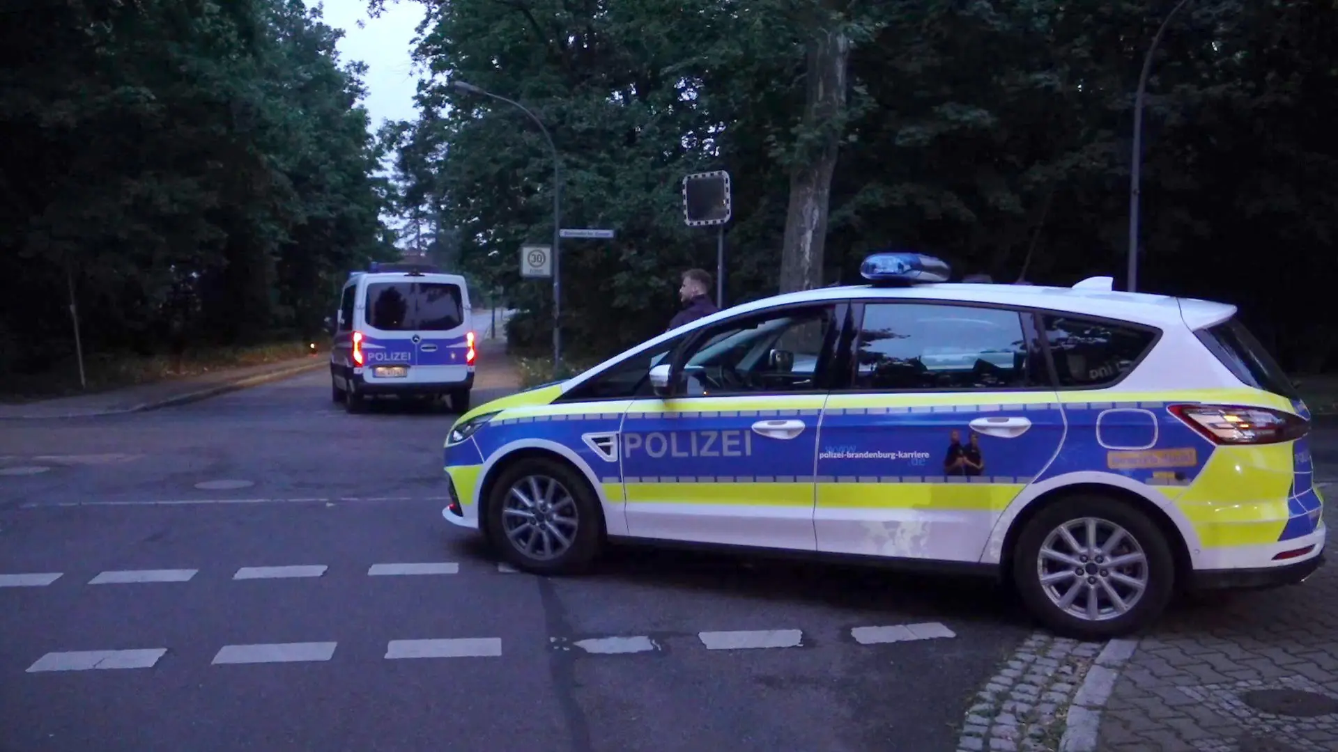 20.07.2023, Brandenburg, Kleinmachnow: Polizeifahrzeuge sind bei einer Suchaktion nach einem freilaufenden gefährlichen Wildtier im Bereich der südlichen Landesgrenze von Berlin zu sehen. Ein gefährliches Wildtier ist in der Nacht zum Donnerstag in Brandenburg entlaufen und hat eine große Suchaktion ausgelöst. Wie die Polizei auf Anfrage der Deutschen Presse-Agentur mitteilte, suchten Einsatzkräfte mit Hubschraubern in Kleinmachnow und angrenzenden Gemeinden nach dem Tier. Foto: Sven Käuler/dpa +++ dpa-Bildfunk +++