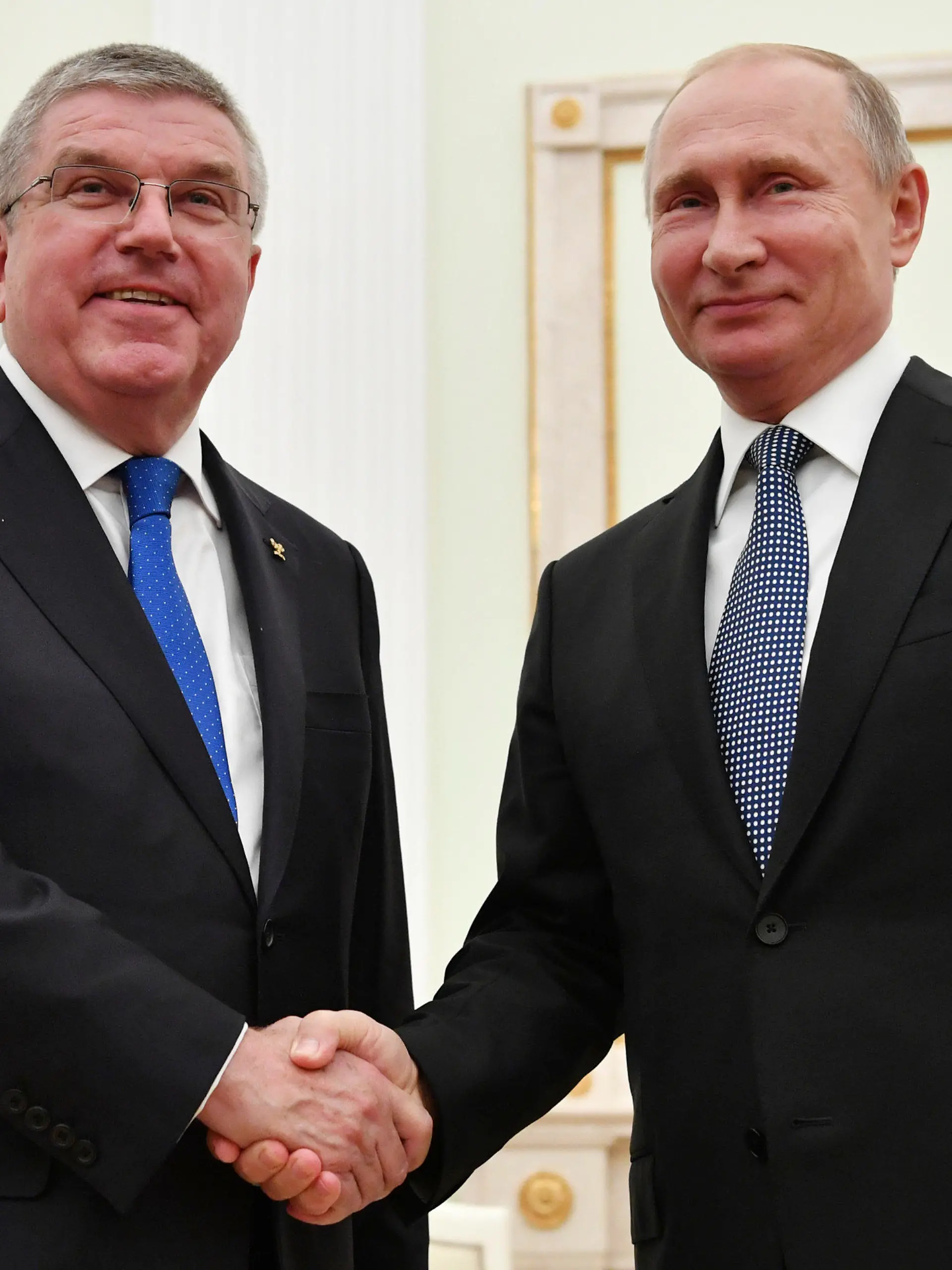 ARCHIV - 15.07.2018, Russland, Moskau: Wladimir Putin (r), Präsident von Russland, gibt Thomas Bach, IOC-Präsident, bei einem Treffen im Kreml die Hand, wenige Stunden vor dem Finale der Fußball-WM zwischen Frankreich und Kroatien. Der IOC-Chef hat nach Angaben eines Sprechers nie einen Orden vom russischen Präsidenten erhalten (zu dpa «IOC-Sprecher: Bach hat nie Orden von Putin erhalten») Foto: Yuri Kadobnov/POOL AFP/dpa +++ dpa-Bildfunk +++