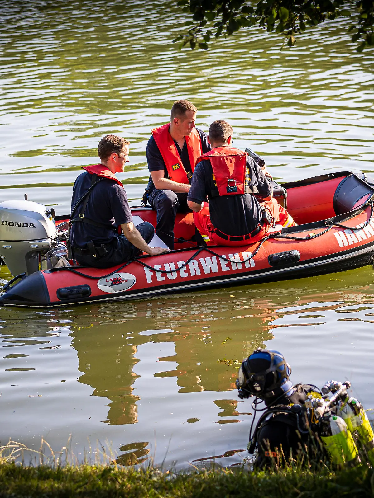 30.06.2022, Niedersachsen, Hannover: Einsatzkräfte sind in einem Boot im Wasser vom Dreiecksteich unterwegs. In dem Baggersee ist ein Mann ertrunken. Foto: Moritz Frankenberg/dpa +++ dpa-Bildfunk +++