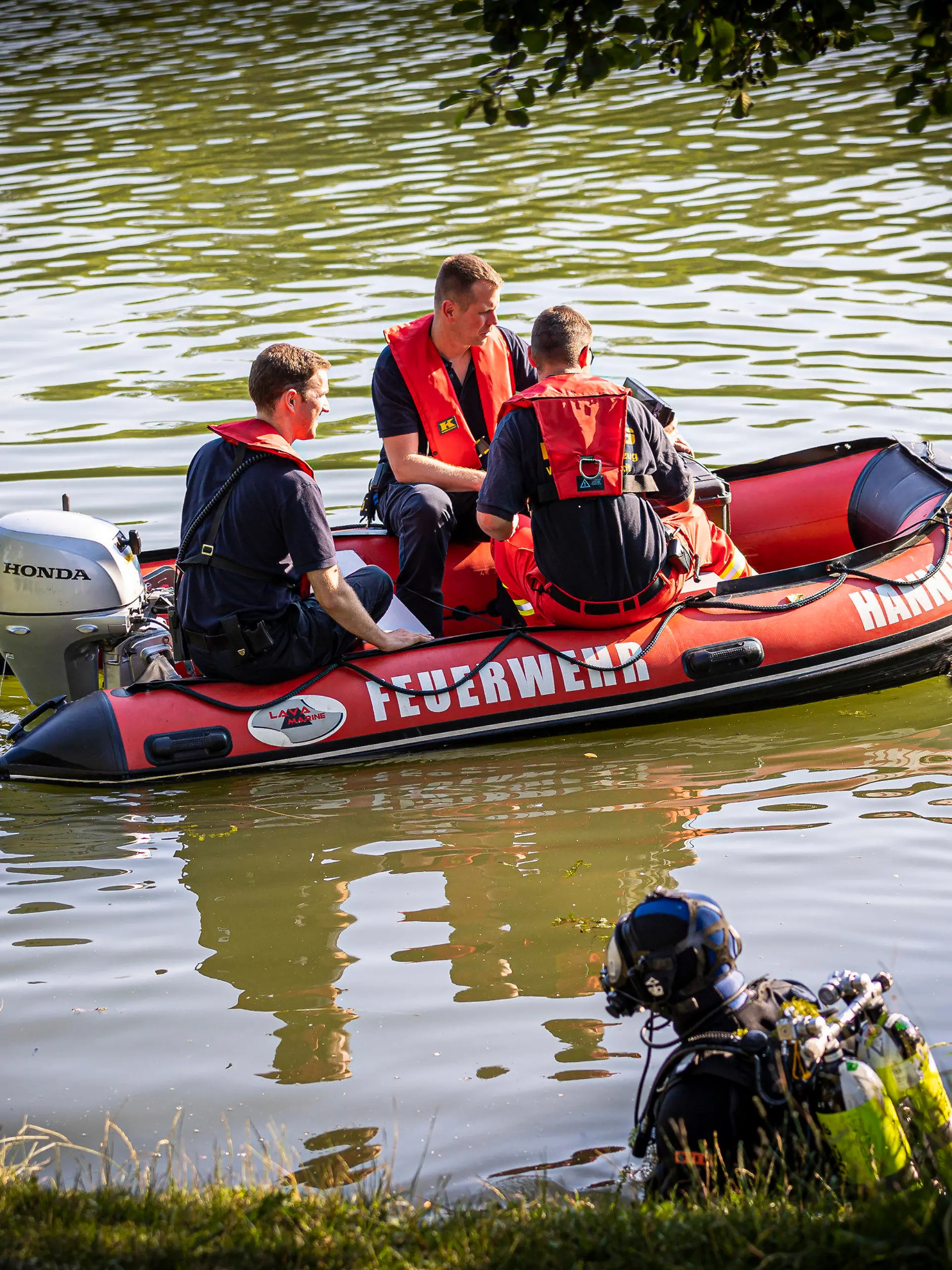 30.06.2022, Niedersachsen, Hannover: Einsatzkräfte sind in einem Boot im Wasser vom Dreiecksteich unterwegs. In dem Baggersee ist ein Mann ertrunken. Foto: Moritz Frankenberg/dpa +++ dpa-Bildfunk +++