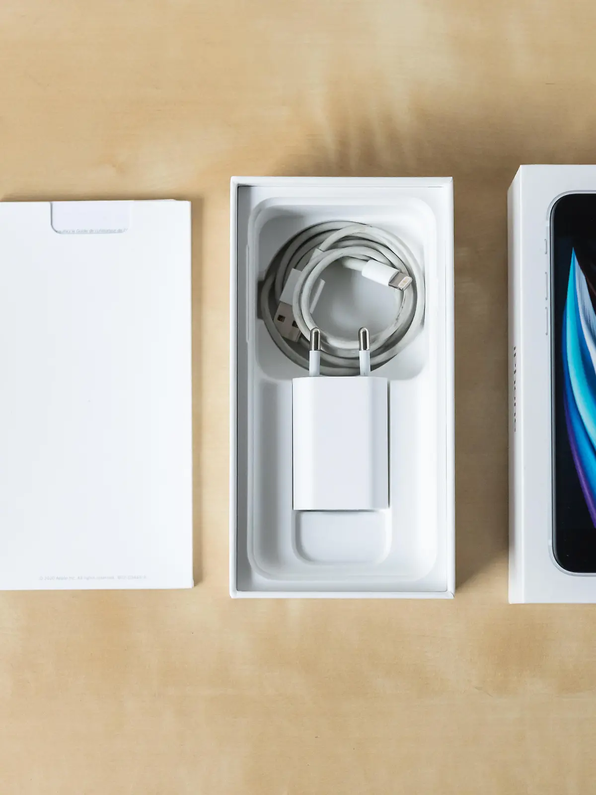 Ein iPhone SE 2020 samt Verpackung und Zubehör liegt auf einem Tisch.
