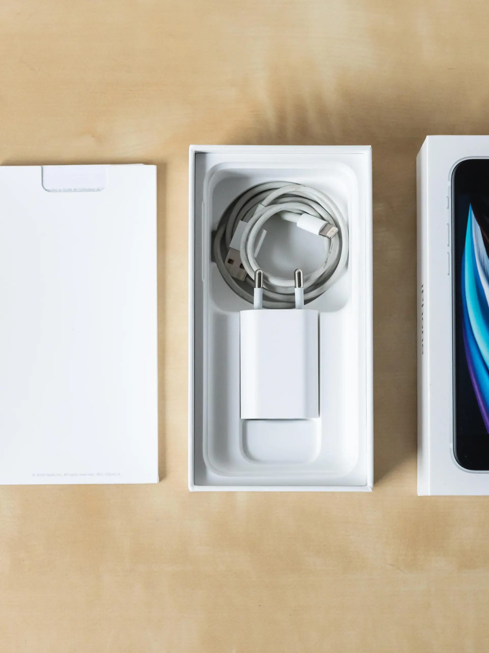 Ein iPhone SE 2020 samt Verpackung und Zubehör liegt auf einem Tisch.