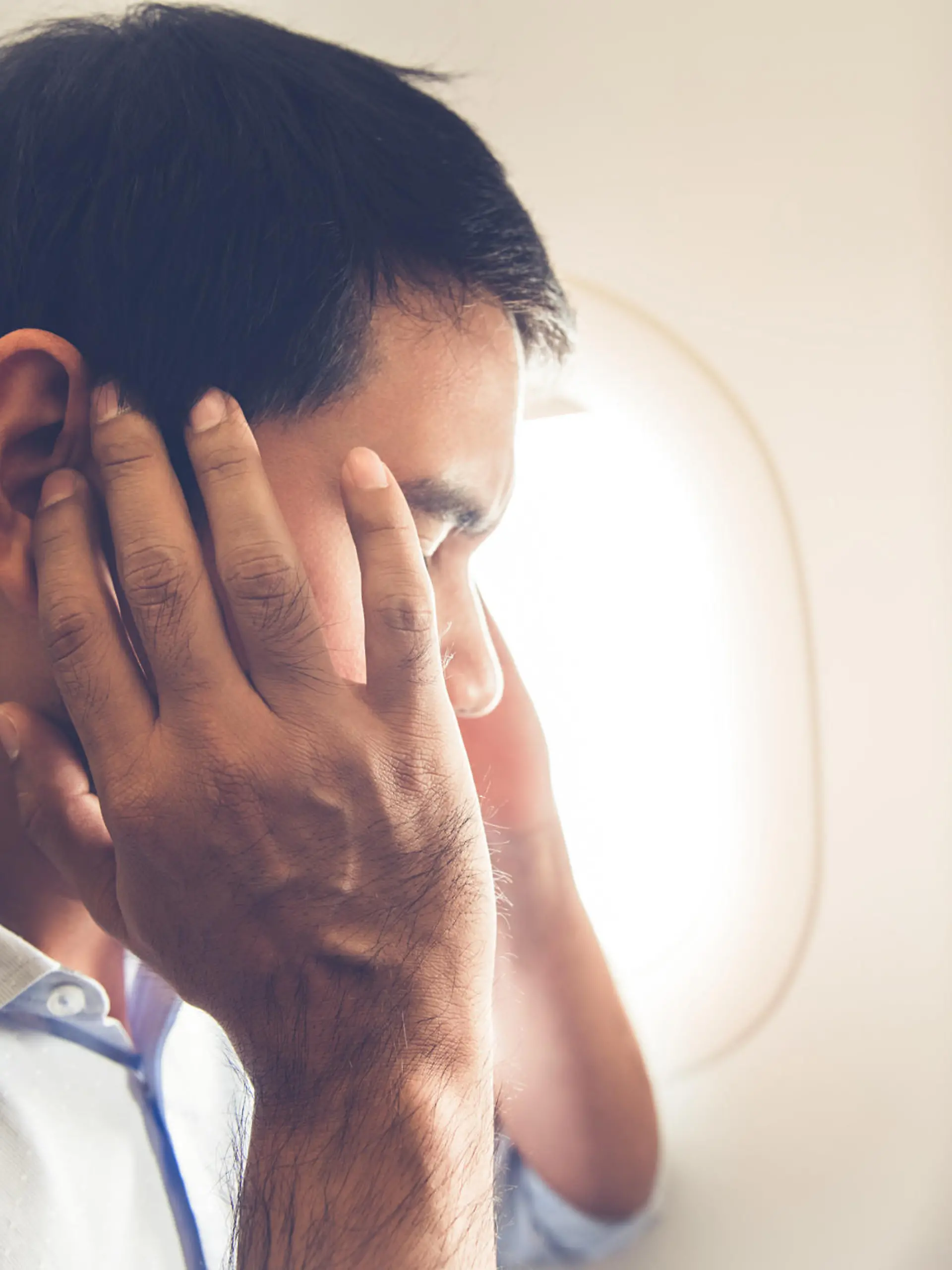 Male passenger having ear pop on the airplane while taking off (or landing)