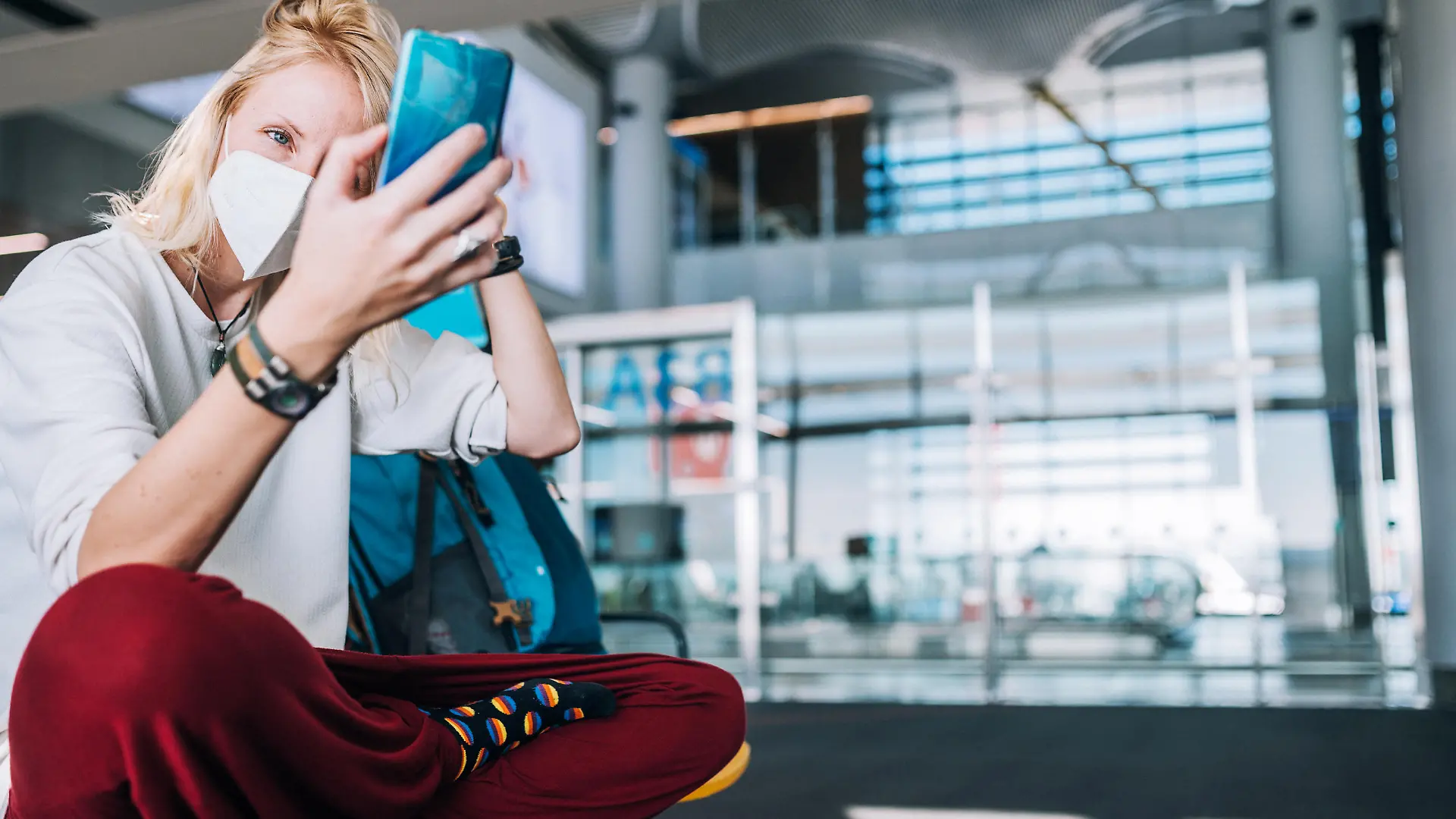 Young woman traveler, in a protective medical mask, sits in the waiting room and doing selfie, video chatting on smartphone
Traveling during Coronavirus pandemic